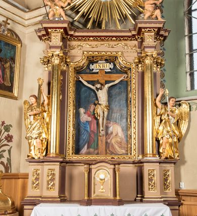 Zdjęcie nr 2: Nastawa ołtarzowa architektoniczna, jednoosiowa i jednokondygnacyjna. Ołtarz prostopadłościenny, drewniany, z drewnianą mensą i z marmurowym portatylem. Antepedium w formie prostokąta ujętego profilowaną ramą. W polu płycina o narożach zdobionych płaskorzeźbioną dekoracją roślinną złożoną z liści stylizowanego akantu oraz umieszczonym w polu veraikonem na tle obłoków i w promienistej glorii. Tabernakulum w kształcie prostopadłościennej skrzynki na niskim cokole, flankowane dwiema kolumnami ustawionymi pod kątem, zamknięte od góry prostym belkowaniem, pośrodku nadwieszonym. Na drzwiczkach płycina w kształcie stojącego prostokąta, zamkniętego łukiem półkolistym, ujęta profilowaną ramą, w polu której umieszczony jest płaskorzeźbiony kielich z hostią.

Retabulum ustawione na podwójnym cokole, flankowane parą zdwojonych pilastrów i ustawionych przed nimi dwiema kolumnami. Podpory dźwigają wyłamane na osi belkowanie z ustawionymi na bokach rzeźbami aniołków z arma Christi (włóczniami). Kolumny wspierają się na bazach, trzony mają gładkie i złocone, a kapitele kompozytowe. Po bokach ołtarza na niskich cokołach ustawione są rzeźby aniołów z narzędziami męki Pańskiej w dłoniach: kolumną biczowania po lewej stronie i włócznią po prawej stronie. W polu, w głębokiej wnęce ujętej szeroką, profilowaną ramą umieszczony jest późnobarokowy krucyfiks na tle malowanej Golgoty i postaci Matki Boskiej, św. Jana Ewangelisty i św. Weroniki. Wnęka od wewnątrz zdobiona jest płaskorzeźbioną winną latoroślą. Cokół dekorowany jest prostokątnymi po bokach płycinami, wypełnionymi stylizowanym akantem. Belkowanie zdobione wicią liści akantu, imposty rozetkami. W zwieńczeniu monumentalna promienista gloria złożona z wiązek promieni o nierównej długości z monogramem Chrystusa na niebieskim tle w polu, otoczonym wieńcem z obłoków. Struktura polichromowana w kolorze jasnego, delikatnego fioletu, płyciny, filary i detale w odcieniu delikatnie ciemniejszym; ornamentyka i profilowania złocone i srebrzone.


