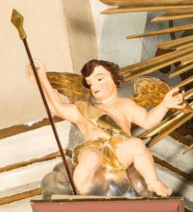 Zdjęcie nr 41: Nastawa ołtarzowa architektoniczna, jednoosiowa i jednokondygnacyjna. Ołtarz prostopadłościenny, drewniany, z drewnianą mensą i z marmurowym portatylem. Antepedium w formie prostokąta ujętego profilowaną ramą. W polu płycina o narożach zdobionych płaskorzeźbioną dekoracją roślinną złożoną z liści stylizowanego akantu oraz umieszczonym w polu veraikonem na tle obłoków i w promienistej glorii. Tabernakulum w kształcie prostopadłościennej skrzynki na niskim cokole, flankowane dwiema kolumnami ustawionymi pod kątem, zamknięte od góry prostym belkowaniem, pośrodku nadwieszonym. Na drzwiczkach płycina w kształcie stojącego prostokąta, zamkniętego łukiem półkolistym, ujęta profilowaną ramą, w polu której umieszczony jest płaskorzeźbiony kielich z hostią.

Retabulum ustawione na podwójnym cokole, flankowane parą zdwojonych pilastrów i ustawionych przed nimi dwiema kolumnami. Podpory dźwigają wyłamane na osi belkowanie z ustawionymi na bokach rzeźbami aniołków z arma Christi (włóczniami). Kolumny wspierają się na bazach, trzony mają gładkie i złocone, a kapitele kompozytowe. Po bokach ołtarza na niskich cokołach ustawione są rzeźby aniołów z narzędziami męki Pańskiej w dłoniach: kolumną biczowania po lewej stronie i włócznią po prawej stronie. W polu, w głębokiej wnęce ujętej szeroką, profilowaną ramą umieszczony jest późnobarokowy krucyfiks na tle malowanej Golgoty i postaci Matki Boskiej, św. Jana Ewangelisty i św. Weroniki. Wnęka od wewnątrz zdobiona jest płaskorzeźbioną winną latoroślą. Cokół dekorowany jest prostokątnymi po bokach płycinami, wypełnionymi stylizowanym akantem. Belkowanie zdobione wicią liści akantu, imposty rozetkami. W zwieńczeniu monumentalna promienista gloria złożona z wiązek promieni o nierównej długości z monogramem Chrystusa na niebieskim tle w polu, otoczonym wieńcem z obłoków. Struktura polichromowana w kolorze jasnego, delikatnego fioletu, płyciny, filary i detale w odcieniu delikatnie ciemniejszym; ornamentyka i profilowania złocone i srebrzone.


