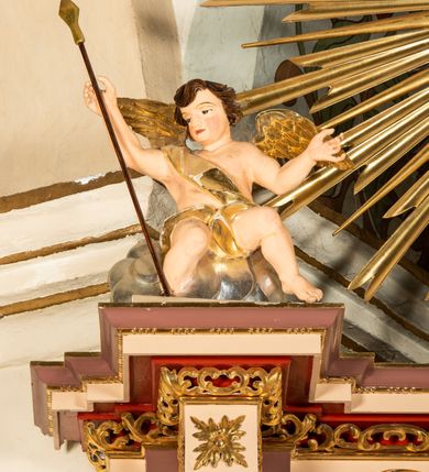 Zdjęcie nr 43: Nastawa ołtarzowa architektoniczna, jednoosiowa i jednokondygnacyjna. Ołtarz prostopadłościenny, drewniany, z drewnianą mensą i z marmurowym portatylem. Antepedium w formie prostokąta ujętego profilowaną ramą. W polu płycina o narożach zdobionych płaskorzeźbioną dekoracją roślinną złożoną z liści stylizowanego akantu oraz umieszczonym w polu veraikonem na tle obłoków i w promienistej glorii. Tabernakulum w kształcie prostopadłościennej skrzynki na niskim cokole, flankowane dwiema kolumnami ustawionymi pod kątem, zamknięte od góry prostym belkowaniem, pośrodku nadwieszonym. Na drzwiczkach płycina w kształcie stojącego prostokąta, zamkniętego łukiem półkolistym, ujęta profilowaną ramą, w polu której umieszczony jest płaskorzeźbiony kielich z hostią.

Retabulum ustawione na podwójnym cokole, flankowane parą zdwojonych pilastrów i ustawionych przed nimi dwiema kolumnami. Podpory dźwigają wyłamane na osi belkowanie z ustawionymi na bokach rzeźbami aniołków z arma Christi (włóczniami). Kolumny wspierają się na bazach, trzony mają gładkie i złocone, a kapitele kompozytowe. Po bokach ołtarza na niskich cokołach ustawione są rzeźby aniołów z narzędziami męki Pańskiej w dłoniach: kolumną biczowania po lewej stronie i włócznią po prawej stronie. W polu, w głębokiej wnęce ujętej szeroką, profilowaną ramą umieszczony jest późnobarokowy krucyfiks na tle malowanej Golgoty i postaci Matki Boskiej, św. Jana Ewangelisty i św. Weroniki. Wnęka od wewnątrz zdobiona jest płaskorzeźbioną winną latoroślą. Cokół dekorowany jest prostokątnymi po bokach płycinami, wypełnionymi stylizowanym akantem. Belkowanie zdobione wicią liści akantu, imposty rozetkami. W zwieńczeniu monumentalna promienista gloria złożona z wiązek promieni o nierównej długości z monogramem Chrystusa na niebieskim tle w polu, otoczonym wieńcem z obłoków. Struktura polichromowana w kolorze jasnego, delikatnego fioletu, płyciny, filary i detale w odcieniu delikatnie ciemniejszym; ornamentyka i profilowania złocone i srebrzone.


