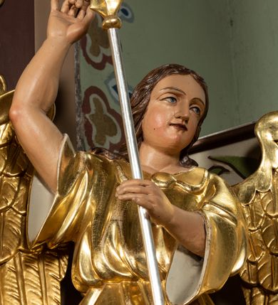 Zdjęcie nr 23: Nastawa ołtarzowa architektoniczna, jednoosiowa i jednokondygnacyjna. Ołtarz prostopadłościenny, drewniany, z drewnianą mensą i z marmurowym portatylem. Antepedium w formie prostokąta ujętego profilowaną ramą. W polu płycina o narożach zdobionych płaskorzeźbioną dekoracją roślinną złożoną z liści stylizowanego akantu oraz umieszczonym w polu veraikonem na tle obłoków i w promienistej glorii. Tabernakulum w kształcie prostopadłościennej skrzynki na niskim cokole, flankowane dwiema kolumnami ustawionymi pod kątem, zamknięte od góry prostym belkowaniem, pośrodku nadwieszonym. Na drzwiczkach płycina w kształcie stojącego prostokąta, zamkniętego łukiem półkolistym, ujęta profilowaną ramą, w polu której umieszczony jest płaskorzeźbiony kielich z hostią.

Retabulum ustawione na podwójnym cokole, flankowane parą zdwojonych pilastrów i ustawionych przed nimi dwiema kolumnami. Podpory dźwigają wyłamane na osi belkowanie z ustawionymi na bokach rzeźbami aniołków z arma Christi (włóczniami). Kolumny wspierają się na bazach, trzony mają gładkie i złocone, a kapitele kompozytowe. Po bokach ołtarza na niskich cokołach ustawione są rzeźby aniołów z narzędziami męki Pańskiej w dłoniach: kolumną biczowania po lewej stronie i włócznią po prawej stronie. W polu, w głębokiej wnęce ujętej szeroką, profilowaną ramą umieszczony jest późnobarokowy krucyfiks na tle malowanej Golgoty i postaci Matki Boskiej, św. Jana Ewangelisty i św. Weroniki. Wnęka od wewnątrz zdobiona jest płaskorzeźbioną winną latoroślą. Cokół dekorowany jest prostokątnymi po bokach płycinami, wypełnionymi stylizowanym akantem. Belkowanie zdobione wicią liści akantu, imposty rozetkami. W zwieńczeniu monumentalna promienista gloria złożona z wiązek promieni o nierównej długości z monogramem Chrystusa na niebieskim tle w polu, otoczonym wieńcem z obłoków. Struktura polichromowana w kolorze jasnego, delikatnego fioletu, płyciny, filary i detale w odcieniu delikatnie ciemniejszym; ornamentyka i profilowania złocone i srebrzone.


