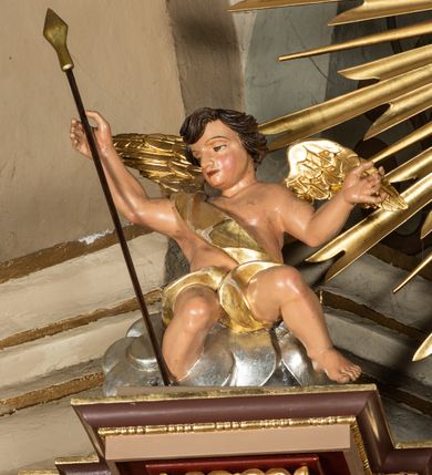 Zdjęcie nr 42: Nastawa ołtarzowa architektoniczna, jednoosiowa i jednokondygnacyjna. Ołtarz prostopadłościenny, drewniany, z drewnianą mensą i z marmurowym portatylem. Antepedium w formie prostokąta ujętego profilowaną ramą. W polu płycina o narożach zdobionych płaskorzeźbioną dekoracją roślinną złożoną z liści stylizowanego akantu oraz umieszczonym w polu veraikonem na tle obłoków i w promienistej glorii. Tabernakulum w kształcie prostopadłościennej skrzynki na niskim cokole, flankowane dwiema kolumnami ustawionymi pod kątem, zamknięte od góry prostym belkowaniem, pośrodku nadwieszonym. Na drzwiczkach płycina w kształcie stojącego prostokąta, zamkniętego łukiem półkolistym, ujęta profilowaną ramą, w polu której umieszczony jest płaskorzeźbiony kielich z hostią.

Retabulum ustawione na podwójnym cokole, flankowane parą zdwojonych pilastrów i ustawionych przed nimi dwiema kolumnami. Podpory dźwigają wyłamane na osi belkowanie z ustawionymi na bokach rzeźbami aniołków z arma Christi (włóczniami). Kolumny wspierają się na bazach, trzony mają gładkie i złocone, a kapitele kompozytowe. Po bokach ołtarza na niskich cokołach ustawione są rzeźby aniołów z narzędziami męki Pańskiej w dłoniach: kolumną biczowania po lewej stronie i włócznią po prawej stronie. W polu, w głębokiej wnęce ujętej szeroką, profilowaną ramą umieszczony jest późnobarokowy krucyfiks na tle malowanej Golgoty i postaci Matki Boskiej, św. Jana Ewangelisty i św. Weroniki. Wnęka od wewnątrz zdobiona jest płaskorzeźbioną winną latoroślą. Cokół dekorowany jest prostokątnymi po bokach płycinami, wypełnionymi stylizowanym akantem. Belkowanie zdobione wicią liści akantu, imposty rozetkami. W zwieńczeniu monumentalna promienista gloria złożona z wiązek promieni o nierównej długości z monogramem Chrystusa na niebieskim tle w polu, otoczonym wieńcem z obłoków. Struktura polichromowana w kolorze jasnego, delikatnego fioletu, płyciny, filary i detale w odcieniu delikatnie ciemniejszym; ornamentyka i profilowania złocone i srebrzone.


