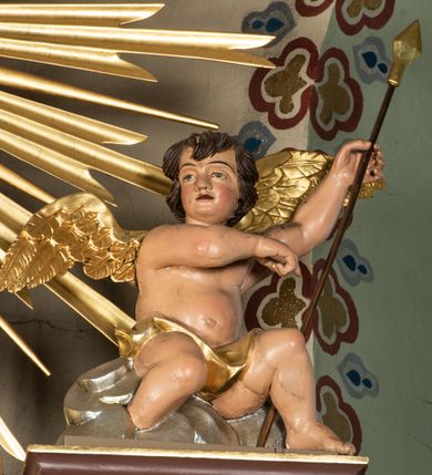 Zdjęcie nr 46: Nastawa ołtarzowa architektoniczna, jednoosiowa i jednokondygnacyjna. Ołtarz prostopadłościenny, drewniany, z drewnianą mensą i z marmurowym portatylem. Antepedium w formie prostokąta ujętego profilowaną ramą. W polu płycina o narożach zdobionych płaskorzeźbioną dekoracją roślinną złożoną z liści stylizowanego akantu oraz umieszczonym w polu veraikonem na tle obłoków i w promienistej glorii. Tabernakulum w kształcie prostopadłościennej skrzynki na niskim cokole, flankowane dwiema kolumnami ustawionymi pod kątem, zamknięte od góry prostym belkowaniem, pośrodku nadwieszonym. Na drzwiczkach płycina w kształcie stojącego prostokąta, zamkniętego łukiem półkolistym, ujęta profilowaną ramą, w polu której umieszczony jest płaskorzeźbiony kielich z hostią.

Retabulum ustawione na podwójnym cokole, flankowane parą zdwojonych pilastrów i ustawionych przed nimi dwiema kolumnami. Podpory dźwigają wyłamane na osi belkowanie z ustawionymi na bokach rzeźbami aniołków z arma Christi (włóczniami). Kolumny wspierają się na bazach, trzony mają gładkie i złocone, a kapitele kompozytowe. Po bokach ołtarza na niskich cokołach ustawione są rzeźby aniołów z narzędziami męki Pańskiej w dłoniach: kolumną biczowania po lewej stronie i włócznią po prawej stronie. W polu, w głębokiej wnęce ujętej szeroką, profilowaną ramą umieszczony jest późnobarokowy krucyfiks na tle malowanej Golgoty i postaci Matki Boskiej, św. Jana Ewangelisty i św. Weroniki. Wnęka od wewnątrz zdobiona jest płaskorzeźbioną winną latoroślą. Cokół dekorowany jest prostokątnymi po bokach płycinami, wypełnionymi stylizowanym akantem. Belkowanie zdobione wicią liści akantu, imposty rozetkami. W zwieńczeniu monumentalna promienista gloria złożona z wiązek promieni o nierównej długości z monogramem Chrystusa na niebieskim tle w polu, otoczonym wieńcem z obłoków. Struktura polichromowana w kolorze jasnego, delikatnego fioletu, płyciny, filary i detale w odcieniu delikatnie ciemniejszym; ornamentyka i profilowania złocone i srebrzone.


