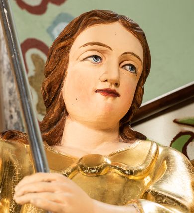 Zdjęcie nr 31: Nastawa ołtarzowa architektoniczna, jednoosiowa i jednokondygnacyjna. Ołtarz prostopadłościenny, drewniany, z drewnianą mensą i z marmurowym portatylem. Antepedium w formie prostokąta ujętego profilowaną ramą. W polu płycina o narożach zdobionych płaskorzeźbioną dekoracją roślinną złożoną z liści stylizowanego akantu oraz umieszczonym w polu veraikonem na tle obłoków i w promienistej glorii. Tabernakulum w kształcie prostopadłościennej skrzynki na niskim cokole, flankowane dwiema kolumnami ustawionymi pod kątem, zamknięte od góry prostym belkowaniem, pośrodku nadwieszonym. Na drzwiczkach płycina w kształcie stojącego prostokąta, zamkniętego łukiem półkolistym, ujęta profilowaną ramą, w polu której umieszczony jest płaskorzeźbiony kielich z hostią.

Retabulum ustawione na podwójnym cokole, flankowane parą zdwojonych pilastrów i ustawionych przed nimi dwiema kolumnami. Podpory dźwigają wyłamane na osi belkowanie z ustawionymi na bokach rzeźbami aniołków z arma Christi (włóczniami). Kolumny wspierają się na bazach, trzony mają gładkie i złocone, a kapitele kompozytowe. Po bokach ołtarza na niskich cokołach ustawione są rzeźby aniołów z narzędziami męki Pańskiej w dłoniach: kolumną biczowania po lewej stronie i włócznią po prawej stronie. W polu, w głębokiej wnęce ujętej szeroką, profilowaną ramą umieszczony jest późnobarokowy krucyfiks na tle malowanej Golgoty i postaci Matki Boskiej, św. Jana Ewangelisty i św. Weroniki. Wnęka od wewnątrz zdobiona jest płaskorzeźbioną winną latoroślą. Cokół dekorowany jest prostokątnymi po bokach płycinami, wypełnionymi stylizowanym akantem. Belkowanie zdobione wicią liści akantu, imposty rozetkami. W zwieńczeniu monumentalna promienista gloria złożona z wiązek promieni o nierównej długości z monogramem Chrystusa na niebieskim tle w polu, otoczonym wieńcem z obłoków. Struktura polichromowana w kolorze jasnego, delikatnego fioletu, płyciny, filary i detale w odcieniu delikatnie ciemniejszym; ornamentyka i profilowania złocone i srebrzone.


