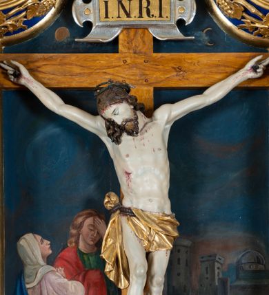 Zdjęcie nr 1: Krucyfiks w typie Cristo morte; postać  Chrystusa umarłego przybitego do krzyża trzema gwoździami. Sylwetka w delikatnym zwisie, o silnie zaznaczonej anatomii ciała, z podkreśloną linią żeber i zaznaczonymi śladami męki. Perizonium w formie tkaniny przewiązanej na sznurze na prawym boku, sięgające kolan i odsłaniające prawe udo. Twarz Jezusa podłużna opadająca na prawe ramię, okolona zarostem; oczy zamknięte, nos podłużny, usta delikatnie otwarte; włosy długie spływające na prawe ramię, na głowie zielona korona cierniowa. Krzyż drewniany, prosty. Nad głową Chrystusa zawieszona tabliczka w kształcie kartusza zdobionego ornamentem okuciowym z napisem „I.N.R.I.” Partie ciała polichromowane naturalistycznie, perizonium złocone.




