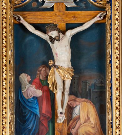 Zdjęcie nr 21: Krucyfiks w typie Cristo morte; postać  Chrystusa umarłego przybitego do krzyża trzema gwoździami. Sylwetka w delikatnym zwisie, o silnie zaznaczonej anatomii ciała, z podkreśloną linią żeber i zaznaczonymi śladami męki. Perizonium w formie tkaniny przewiązanej na sznurze na prawym boku, sięgające kolan i odsłaniające prawe udo. Twarz Jezusa podłużna opadająca na prawe ramię, okolona zarostem; oczy zamknięte, nos podłużny, usta delikatnie otwarte; włosy długie spływające na prawe ramię, na głowie zielona korona cierniowa. Krzyż drewniany, prosty. Nad głową Chrystusa zawieszona tabliczka w kształcie kartusza zdobionego ornamentem okuciowym z napisem „I.N.R.I.” Partie ciała polichromowane naturalistycznie, perizonium złocone.




