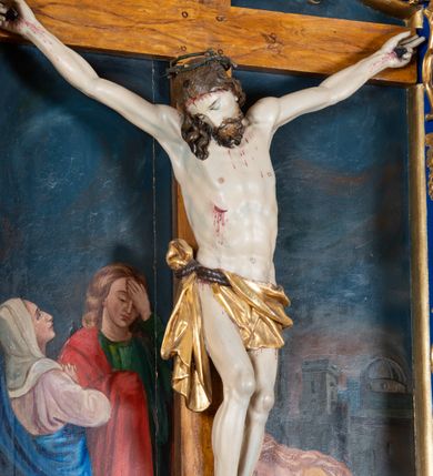 Zdjęcie nr 20: Krucyfiks w typie Cristo morte; postać  Chrystusa umarłego przybitego do krzyża trzema gwoździami. Sylwetka w delikatnym zwisie, o silnie zaznaczonej anatomii ciała, z podkreśloną linią żeber i zaznaczonymi śladami męki. Perizonium w formie tkaniny przewiązanej na sznurze na prawym boku, sięgające kolan i odsłaniające prawe udo. Twarz Jezusa podłużna opadająca na prawe ramię, okolona zarostem; oczy zamknięte, nos podłużny, usta delikatnie otwarte; włosy długie spływające na prawe ramię, na głowie zielona korona cierniowa. Krzyż drewniany, prosty. Nad głową Chrystusa zawieszona tabliczka w kształcie kartusza zdobionego ornamentem okuciowym z napisem „I.N.R.I.” Partie ciała polichromowane naturalistycznie, perizonium złocone.




