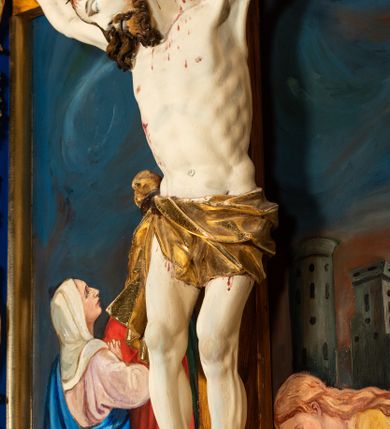 Zdjęcie nr 7: Krucyfiks w typie Cristo morte; postać  Chrystusa umarłego przybitego do krzyża trzema gwoździami. Sylwetka w delikatnym zwisie, o silnie zaznaczonej anatomii ciała, z podkreśloną linią żeber i zaznaczonymi śladami męki. Perizonium w formie tkaniny przewiązanej na sznurze na prawym boku, sięgające kolan i odsłaniające prawe udo. Twarz Jezusa podłużna opadająca na prawe ramię, okolona zarostem; oczy zamknięte, nos podłużny, usta delikatnie otwarte; włosy długie spływające na prawe ramię, na głowie zielona korona cierniowa. Krzyż drewniany, prosty. Nad głową Chrystusa zawieszona tabliczka w kształcie kartusza zdobionego ornamentem okuciowym z napisem „I.N.R.I.” Partie ciała polichromowane naturalistycznie, perizonium złocone.





