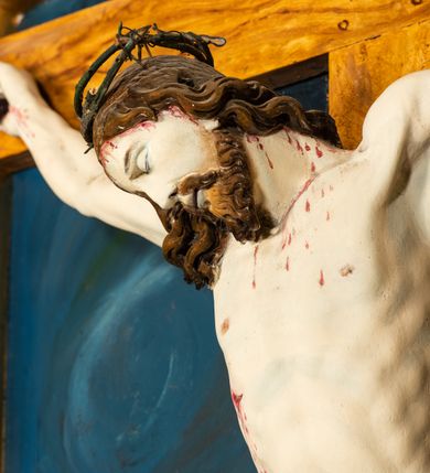 Zdjęcie nr 10: Krucyfiks w typie Cristo morte; postać  Chrystusa umarłego przybitego do krzyża trzema gwoździami. Sylwetka w delikatnym zwisie, o silnie zaznaczonej anatomii ciała, z podkreśloną linią żeber i zaznaczonymi śladami męki. Perizonium w formie tkaniny przewiązanej na sznurze na prawym boku, sięgające kolan i odsłaniające prawe udo. Twarz Jezusa podłużna opadająca na prawe ramię, okolona zarostem; oczy zamknięte, nos podłużny, usta delikatnie otwarte; włosy długie spływające na prawe ramię, na głowie zielona korona cierniowa. Krzyż drewniany, prosty. Nad głową Chrystusa zawieszona tabliczka w kształcie kartusza zdobionego ornamentem okuciowym z napisem „I.N.R.I.” Partie ciała polichromowane naturalistycznie, perizonium złocone.




