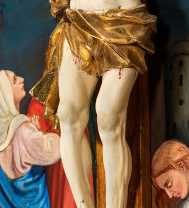 Zdjęcie nr 9: Krucyfiks w typie Cristo morte; postać  Chrystusa umarłego przybitego do krzyża trzema gwoździami. Sylwetka w delikatnym zwisie, o silnie zaznaczonej anatomii ciała, z podkreśloną linią żeber i zaznaczonymi śladami męki. Perizonium w formie tkaniny przewiązanej na sznurze na prawym boku, sięgające kolan i odsłaniające prawe udo. Twarz Jezusa podłużna opadająca na prawe ramię, okolona zarostem; oczy zamknięte, nos podłużny, usta delikatnie otwarte; włosy długie spływające na prawe ramię, na głowie zielona korona cierniowa. Krzyż drewniany, prosty. Nad głową Chrystusa zawieszona tabliczka w kształcie kartusza zdobionego ornamentem okuciowym z napisem „I.N.R.I.” Partie ciała polichromowane naturalistycznie, perizonium złocone.




