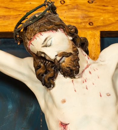 Zdjęcie nr 13: Krucyfiks w typie Cristo morte; postać  Chrystusa umarłego przybitego do krzyża trzema gwoździami. Sylwetka w delikatnym zwisie, o silnie zaznaczonej anatomii ciała, z podkreśloną linią żeber i zaznaczonymi śladami męki. Perizonium w formie tkaniny przewiązanej na sznurze na prawym boku, sięgające kolan i odsłaniające prawe udo. Twarz Jezusa podłużna opadająca na prawe ramię, okolona zarostem; oczy zamknięte, nos podłużny, usta delikatnie otwarte; włosy długie spływające na prawe ramię, na głowie zielona korona cierniowa. Krzyż drewniany, prosty. Nad głową Chrystusa zawieszona tabliczka w kształcie kartusza zdobionego ornamentem okuciowym z napisem „I.N.R.I.” Partie ciała polichromowane naturalistycznie, perizonium złocone.




