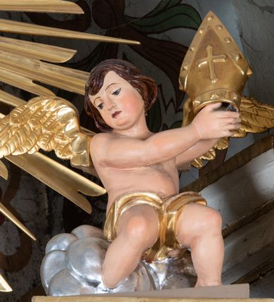 Zdjęcie nr 19: Nastawa ołtarzowa architektoniczna, jednoosiowa i jednokondygnacyjna. Ołtarz prostopadłościenny, drewniany z drewnianą mensą i z marmurowym portatylem. Antepedium w formie prostokąta ujętego profilowaną ramą. W polu płycina o narożach zdobionych płaskorzeźbioną dekoracją roślinną złożoną z liści stylizowanego akantu oraz umieszczonym w polu Barankiem Paschalnym na księdze z siedmioma pieczęciami na czerwonym tle w otoczeniu obłoków i promienistej glorii. Tabernakulum w kształcie prostopadłościennej skrzynki na niskim cokole, flankowane dwiema kolumnami ustawionymi pod kątem, zamknięte od góry prostym belkowaniem, pośrodku nadwieszonym. Na drzwiczkach płycina w kształcie stojącego prostokąta, zamkniętego łukiem półkolistym, ujęta profilowaną ramą, w polu umieszczony jest płaskorzeźbiony kielich z hostią.

Retabulum ustawione na podwójnym cokole, flankowane parą zdwojonych pilastrów i ustawionych przed nimi dwiema kolumnami. Podpory dźwigają wyłamane na osi belkowanie z ustawionymi na bokach rzeźbami aniołków, które trzymają w dłoniach pastorał oraz infułę. Kolumny wspierają się na bazach, trzony mają gładkie i złocone, a kapitele kompozytowe. Po bokach ołtarza na niskich cokołach ustawione są rzeźby: św. Piotra po lewej i św. Pawła po prawej stronie. W polu, w głębokiej wnęce ujętej szeroką, profilowaną ramą umieszczony jest obraz Najświętszego Serca Pana Jezusa. Wnęka od wewnątrz zdobiona płaskorzeźbioną winną latoroślą. Cokół dekorowany jest prostokątnymi płycinami, po bokach wypełnionymi stylizowanym akantem, a pośrodku gablotką z wotami. Belkowanie zdobione wicią z liści akantu oraz rozetami na impostach. W zwieńczeniu monumentalna promienista gloria złożona z wiązek promieni o nierównej długości z monogramem maryjnym na niebieskim tle w polu, otoczonym wieńcem z obłoków. Struktura polichromowana w kolorze jasnego, delikatnego fioletu, płyciny, filary i detale w odcieniu delikatnie ciemniejszym; ornamentyka i profilowania złocone i srebrzone.
