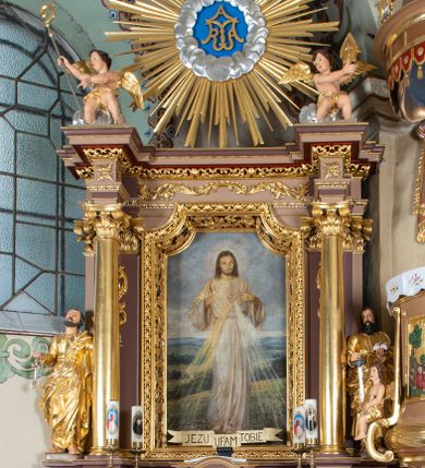 Zdjęcie nr 1: Nastawa ołtarzowa architektoniczna, jednoosiowa i jednokondygnacyjna. Ołtarz prostopadłościenny, drewniany z drewnianą mensą i z marmurowym portatylem. Antepedium w formie prostokąta ujętego profilowaną ramą. W polu płycina o narożach zdobionych płaskorzeźbioną dekoracją roślinną złożoną z liści stylizowanego akantu oraz umieszczonym w polu Barankiem Paschalnym na księdze z siedmioma pieczęciami na czerwonym tle w otoczeniu obłoków i promienistej glorii. Tabernakulum w kształcie prostopadłościennej skrzynki na niskim cokole, flankowane dwiema kolumnami ustawionymi pod kątem, zamknięte od góry prostym belkowaniem, pośrodku nadwieszonym. Na drzwiczkach płycina w kształcie stojącego prostokąta, zamkniętego łukiem półkolistym, ujęta profilowaną ramą, w polu umieszczony jest płaskorzeźbiony kielich z hostią.

Retabulum ustawione na podwójnym cokole, flankowane parą zdwojonych pilastrów i ustawionych przed nimi dwiema kolumnami. Podpory dźwigają wyłamane na osi belkowanie z ustawionymi na bokach rzeźbami aniołków, które trzymają w dłoniach pastorał oraz infułę. Kolumny wspierają się na bazach, trzony mają gładkie i złocone, a kapitele kompozytowe. Po bokach ołtarza na niskich cokołach ustawione są rzeźby: św. Piotra po lewej i św. Pawła po prawej stronie. W polu, w głębokiej wnęce ujętej szeroką, profilowaną ramą umieszczony jest obraz Najświętszego Serca Pana Jezusa. Wnęka od wewnątrz zdobiona płaskorzeźbioną winną latoroślą. Cokół dekorowany jest prostokątnymi płycinami, po bokach wypełnionymi stylizowanym akantem, a pośrodku gablotką z wotami. Belkowanie zdobione wicią z liści akantu oraz rozetami na impostach. W zwieńczeniu monumentalna promienista gloria złożona z wiązek promieni o nierównej długości z monogramem maryjnym na niebieskim tle w polu, otoczonym wieńcem z obłoków. Struktura polichromowana w kolorze jasnego, delikatnego fioletu, płyciny, filary i detale w odcieniu delikatnie ciemniejszym; ornamentyka i profilowania złocone i srebrzone.
