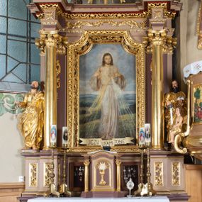 Zdjęcie nr 1: Nastawa ołtarzowa architektoniczna, jednoosiowa i jednokondygnacyjna. Ołtarz prostopadłościenny, drewniany z drewnianą mensą i z marmurowym portatylem. Antepedium w formie prostokąta ujętego profilowaną ramą. W polu płycina o narożach zdobionych płaskorzeźbioną dekoracją roślinną złożoną z liści stylizowanego akantu oraz umieszczonym w polu Barankiem Paschalnym na księdze z siedmioma pieczęciami na czerwonym tle w otoczeniu obłoków i promienistej glorii. Tabernakulum w kształcie prostopadłościennej skrzynki na niskim cokole, flankowane dwiema kolumnami ustawionymi pod kątem, zamknięte od góry prostym belkowaniem, pośrodku nadwieszonym. Na drzwiczkach płycina w kształcie stojącego prostokąta, zamkniętego łukiem półkolistym, ujęta profilowaną ramą, w polu umieszczony jest płaskorzeźbiony kielich z hostią.

Retabulum ustawione na podwójnym cokole, flankowane parą zdwojonych pilastrów i ustawionych przed nimi dwiema kolumnami. Podpory dźwigają wyłamane na osi belkowanie z ustawionymi na bokach rzeźbami aniołków, które trzymają w dłoniach pastorał oraz infułę. Kolumny wspierają się na bazach, trzony mają gładkie i złocone, a kapitele kompozytowe. Po bokach ołtarza na niskich cokołach ustawione są rzeźby: św. Piotra po lewej i św. Pawła po prawej stronie. W polu, w głębokiej wnęce ujętej szeroką, profilowaną ramą umieszczony jest obraz Najświętszego Serca Pana Jezusa. Wnęka od wewnątrz zdobiona płaskorzeźbioną winną latoroślą. Cokół dekorowany jest prostokątnymi płycinami, po bokach wypełnionymi stylizowanym akantem, a pośrodku gablotką z wotami. Belkowanie zdobione wicią z liści akantu oraz rozetami na impostach. W zwieńczeniu monumentalna promienista gloria złożona z wiązek promieni o nierównej długości z monogramem maryjnym na niebieskim tle w polu, otoczonym wieńcem z obłoków. Struktura polichromowana w kolorze jasnego, delikatnego fioletu, płyciny, filary i detale w odcieniu delikatnie ciemniejszym; ornamentyka i profilowania złocone i srebrzone.
