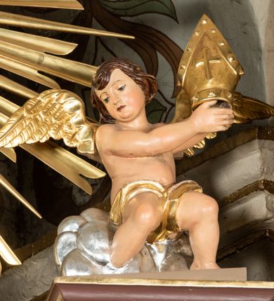 Zdjęcie nr 20: Nastawa ołtarzowa architektoniczna, jednoosiowa i jednokondygnacyjna. Ołtarz prostopadłościenny, drewniany z drewnianą mensą i z marmurowym portatylem. Antepedium w formie prostokąta ujętego profilowaną ramą. W polu płycina o narożach zdobionych płaskorzeźbioną dekoracją roślinną złożoną z liści stylizowanego akantu oraz umieszczonym w polu Barankiem Paschalnym na księdze z siedmioma pieczęciami na czerwonym tle w otoczeniu obłoków i promienistej glorii. Tabernakulum w kształcie prostopadłościennej skrzynki na niskim cokole, flankowane dwiema kolumnami ustawionymi pod kątem, zamknięte od góry prostym belkowaniem, pośrodku nadwieszonym. Na drzwiczkach płycina w kształcie stojącego prostokąta, zamkniętego łukiem półkolistym, ujęta profilowaną ramą, w polu umieszczony jest płaskorzeźbiony kielich z hostią.

Retabulum ustawione na podwójnym cokole, flankowane parą zdwojonych pilastrów i ustawionych przed nimi dwiema kolumnami. Podpory dźwigają wyłamane na osi belkowanie z ustawionymi na bokach rzeźbami aniołków, które trzymają w dłoniach pastorał oraz infułę. Kolumny wspierają się na bazach, trzony mają gładkie i złocone, a kapitele kompozytowe. Po bokach ołtarza na niskich cokołach ustawione są rzeźby: św. Piotra po lewej i św. Pawła po prawej stronie. W polu, w głębokiej wnęce ujętej szeroką, profilowaną ramą umieszczony jest obraz Najświętszego Serca Pana Jezusa. Wnęka od wewnątrz zdobiona płaskorzeźbioną winną latoroślą. Cokół dekorowany jest prostokątnymi płycinami, po bokach wypełnionymi stylizowanym akantem, a pośrodku gablotką z wotami. Belkowanie zdobione wicią z liści akantu oraz rozetami na impostach. W zwieńczeniu monumentalna promienista gloria złożona z wiązek promieni o nierównej długości z monogramem maryjnym na niebieskim tle w polu, otoczonym wieńcem z obłoków. Struktura polichromowana w kolorze jasnego, delikatnego fioletu, płyciny, filary i detale w odcieniu delikatnie ciemniejszym; ornamentyka i profilowania złocone i srebrzone.
