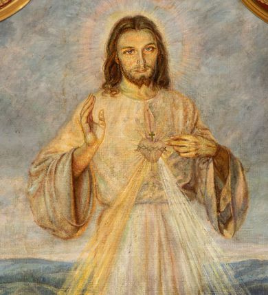 Zdjęcie nr 3: Obraz w kształcie stojącego prostokąta o wklęsłych górnych narożach z przedstawieniem Najświętszego Serca Jezusa. W centrum kompozycji ukazany jest Jezus w całej postaci, prawą ręką czyni gest błogosławieństwa, lewą wskazuje na gorejące na piersi serce. Twarz podłużna z długim i wąskim nosem, dużymi oczami, okolona krótką brodą, rozdzieloną na dwa, małe pukle. Włosy długie, ciemnobrązowe, z przedziałkiem pośrodku, opadające na plecy i ramiona bujnymi falami. Jezus ubrany jest w długą, jasną suknię, przewiązaną w talii. Na dłoniach i stopach ma widoczne ślady męki. Wokół głowy ma okrągły nimb. Od serca oplecionego koroną cierniową odchodzą dwa strumienie promieni, po lewej złoty, a po prawej biały. Chrystus ukazany został na kwitnącej łące, w oddali widoczny jest polny krajobraz i jasne niebo. Kolorystyka pastelowa, miękki i delikatny modelunek. W dolnej części kompozycji złota banderola z napisem „JEZU UFAM TOBIE”. W dolnym, lewym narożu sygnatura: „A(dolf) Hyła”, a po prawej data „1951”. Rama wnęki drewniana, szeroka, profilowana, zdobiona winną latoroślą. 

