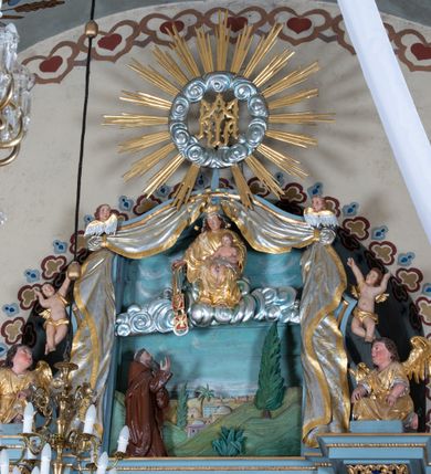 Zdjęcie nr 3: Ołtarz architektoniczny, jednoosiowy, jednokondygnacyjny ze zwieńczeniem. Mensa w kształcie nieregularnego prostopadłościanu, poprzedzona dwoma stopniami. Antepedium w formie prostokątnej płyciny, wewnątrz której w narożach są stylizowane dekoracje kwiatowe, a pośrodku równoramienna gwiazda w kartuszu. Tabernakulum w kształcie prostokątnej skrzynki, flankowane w narożach ustawionymi pod kątem pilastrami w formie liści, podtrzymującymi wyłamujący się gzyms. Drzwiczki zamknięte półkoliście z aplikowanym motywem kielicha oraz medalionem z napisem IHS w niewielkiej glorii. Drzwiczki obite srebrzoną blachą, boki i dekoracje złocone, gzyms w kolorze jasnoniebieskim. 

Cokół nastawy zdobiony kratkowaniem, a po bokach prostokątnymi płycinami ze stylizowaną dekoracją akantową. Retabulum flankowane zdwojoną parą pilastrów i stojącą przed nimi parą kolumn. Podpory dźwigają wyłamane na osi belkowanie. Kolumny ustawione na bazach, trzony gładkie i złocone, wybrzuszone pośrodku, kapitele kompozytowe. W polu głównym w niszy zamkniętej półkolistym łukiem umieszczony jest obraz Matki Boskiej z Dzieciątkiem, a powyżej rzeźba Boga Ojca. Na boku ołtarza znajdują się rzeźby: św. Dominika po lewej i św. Jacka po prawej stronie. Na belkowaniu usadzona jest para aniołków. Zwieńczenie o fantazyjnym kształcie zbliżonym do stojącego prostokąta z płaskorzeźbioną sceną ofiarowania szkaplerza św. Szymonowi Stockowi. U góry zwieńczenia podpięta srebrzona kotara o złoconym brzegu, spływająca na jego boki zwieńczenia. W górnej partii, po bokach para aniołków z wzniesionymi do góry rękami oraz dwie uskrzydlone główki anielskie. Na szczycie nastawy zatknięta jest promienista gloria złożona z wiązek promieni o nierównej długości z monogramem maryjnym otoczonym przez wieniec z obłoków w polu. Po bokach nastawy ołtarzowej umieszczone są uszaki utworzone ze stylizowanego akantu. Polichromia ołtarza w kolorze jasnoniebieskim, dekoracje ornamentalne oraz detale złocone i srebrzone. 
