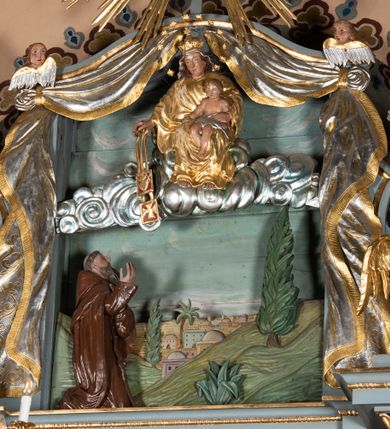 Zdjęcie nr 31: Ołtarz architektoniczny, jednoosiowy, jednokondygnacyjny ze zwieńczeniem. Mensa w kształcie nieregularnego prostopadłościanu, poprzedzona dwoma stopniami. Antepedium w formie prostokątnej płyciny, wewnątrz której w narożach są stylizowane dekoracje kwiatowe, a pośrodku równoramienna gwiazda w kartuszu. Tabernakulum w kształcie prostokątnej skrzynki, flankowane w narożach ustawionymi pod kątem pilastrami w formie liści, podtrzymującymi wyłamujący się gzyms. Drzwiczki zamknięte półkoliście z aplikowanym motywem kielicha oraz medalionem z napisem IHS w niewielkiej glorii. Drzwiczki obite srebrzoną blachą, boki i dekoracje złocone, gzyms w kolorze jasnoniebieskim. 

Cokół nastawy zdobiony kratkowaniem, a po bokach prostokątnymi płycinami ze stylizowaną dekoracją akantową. Retabulum flankowane zdwojoną parą pilastrów i stojącą przed nimi parą kolumn. Podpory dźwigają wyłamane na osi belkowanie. Kolumny ustawione na bazach, trzony gładkie i złocone, wybrzuszone pośrodku, kapitele kompozytowe. W polu głównym w niszy zamkniętej półkolistym łukiem umieszczony jest obraz Matki Boskiej z Dzieciątkiem, a powyżej rzeźba Boga Ojca. Na boku ołtarza znajdują się rzeźby: św. Dominika po lewej i św. Jacka po prawej stronie. Na belkowaniu usadzona jest para aniołków. Zwieńczenie o fantazyjnym kształcie zbliżonym do stojącego prostokąta z płaskorzeźbioną sceną ofiarowania szkaplerza św. Szymonowi Stockowi. U góry zwieńczenia podpięta srebrzona kotara o złoconym brzegu, spływająca na jego boki zwieńczenia. W górnej partii, po bokach para aniołków z wzniesionymi do góry rękami oraz dwie uskrzydlone główki anielskie. Na szczycie nastawy zatknięta jest promienista gloria złożona z wiązek promieni o nierównej długości z monogramem maryjnym otoczonym przez wieniec z obłoków w polu. Po bokach nastawy ołtarzowej umieszczone są uszaki utworzone ze stylizowanego akantu. Polichromia ołtarza w kolorze jasnoniebieskim, dekoracje ornamentalne oraz detale złocone i srebrzone. 
