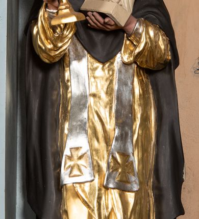 Zdjęcie nr 2: Rzeźba św. Jacka ustawiona na niskim, dwustrefowym cokole. Święty ukazany frontalnie z figurką Matki Boskiej w lewej ręce i puszką na komunikanty w prawej. Twarz pełna z długim nosem i małymi oczami o silnie zarumienionych policzkach; na głowie tonsura. Święty ubrany jest w złocony habit dominikański, czarny płaszcz ze srebrzonym kapturem oraz srebrzoną, długą stułę sięgającą, aż do kolan; na stopach ma założone czarne, pełne buty. Polichromia w odsłoniętych partiach ciała naturalistyczna, puszka złocona, figurka Matki Boskiej polichromowana w kolorze kości słoniowej.

