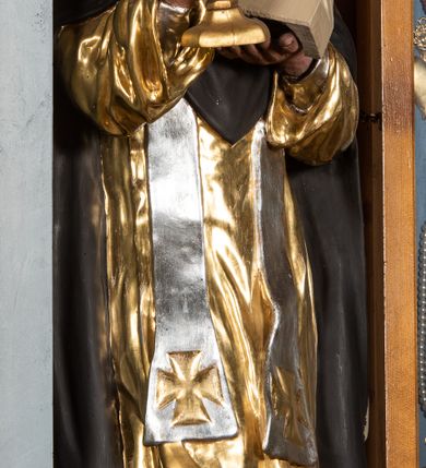 Zdjęcie nr 3: Rzeźba św. Jacka ustawiona na niskim, dwustrefowym cokole. Święty ukazany frontalnie z figurką Matki Boskiej w lewej ręce i puszką na komunikanty w prawej. Twarz pełna z długim nosem i małymi oczami o silnie zarumienionych policzkach; na głowie tonsura. Święty ubrany jest w złocony habit dominikański, czarny płaszcz ze srebrzonym kapturem oraz srebrzoną, długą stułę sięgającą, aż do kolan; na stopach ma założone czarne, pełne buty. Polichromia w odsłoniętych partiach ciała naturalistyczna, puszka złocona, figurka Matki Boskiej polichromowana w kolorze kości słoniowej.

