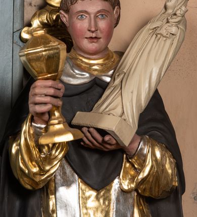 Zdjęcie nr 4: Rzeźba św. Jacka ustawiona na niskim, dwustrefowym cokole. Święty ukazany frontalnie z figurką Matki Boskiej w lewej ręce i puszką na komunikanty w prawej. Twarz pełna z długim nosem i małymi oczami o silnie zarumienionych policzkach; na głowie tonsura. Święty ubrany jest w złocony habit dominikański, czarny płaszcz ze srebrzonym kapturem oraz srebrzoną, długą stułę sięgającą, aż do kolan; na stopach ma założone czarne, pełne buty. Polichromia w odsłoniętych partiach ciała naturalistyczna, puszka złocona, figurka Matki Boskiej polichromowana w kolorze kości słoniowej.

