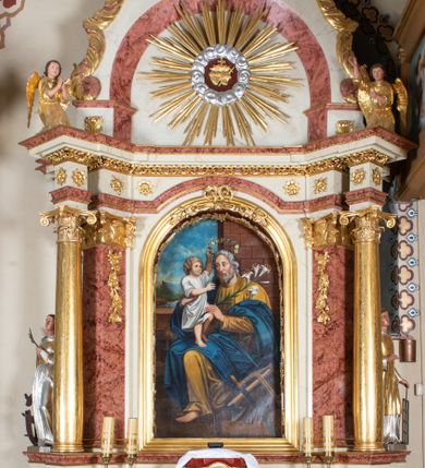Zdjęcie nr 1: Nastawa ołtarzowa architektoniczna, jednoosiowa, jednokondygnacyjna ze zwieńczeniem. Ołtarz prostopadłościenny, drewniany z drewnianą mensą i z marmurowym portatylem. Antepedium w formie prostokąta ujętego profilowaną ramą. W polu marmoryzowana płycina o narożach zdobionych płaskorzeźbioną dekoracją roślinną złożoną z liści akantu oraz nałożonymi na siebie łacińskim krzyżem z kotwicą i gorejącym sercem oplecionym wicią z róż w polu. Tabernakulum w kształcie prostopadłościennej skrzynki na niskim cokole, flankowane dwoma pilastrami ustawionymi pod kątem, zdobionymi wicią z liści akantu; zamknięte od góry prostym belkowaniem, pośrodku falującym. Na drzwiczkach płycina w kształcie stojącego prostokąta, zamkniętego łukiem półkolistym, ujęta profilowaną ramą, w polu której umieszczone jest płaskorzeźbione gorejące serce osadzone na gałązce róży; tło czerwone.

Retabulum na zdwojonym cokole, flankowane ustawionymi pod kątem w jednej linii parami pilastrów, filarów oraz kolumn na przodzie. Podpory dźwigają wyłamane na osi belkowanie z ustawionymi na bokach rzeźbami aniołków. Trzony filarów są marmoryzowane; trzony kolumn delikatnie zwężające się ku górze, złocone, zdobione pionowymi pasami, co drugi wypełniony pnącą się ku górze rytą wicią z liści dębu lub z liści klonu; kapitele podpór kompozytowe.  Po bokach ołtarza na niskich cokołach ustawione pod kątem rzeźby św. Katarzyny Aleksandryjskiej po lewej i św. Wawrzyńca po prawej stronie. W polu, w głębokiej wnęce ujętej szeroką, profilowaną ramą umieszczony jest obraz św. Józefa z Dzieciątkiem. Wnęka od wewnątrz zdobiona płaskorzeźbioną winną latoroślą. Cokół dekorowany jest prostokątnymi, marmoryzowanymi płycinami; fryz złoconymi rozetami.

Zwieńczenie monumentalne, o fantazyjnym kształcie, po bokach ujęte wolutami zdobionymi liśćmi akantu, zamknięte od góry prostym gzymsem w formie nadwieszonego łuku z zatkniętym na szczycie łacińskim krzyżykiem. W polu, w półkolistej wnęce promienista gloria z dwoma gorejącymi sercami, z których jedno przebite jest mieczem, umieszczonym w otoku z obłoków.

Struktura w kolorze jasnobeżowym, płyciny, filary i detale marmoryzowana w kolorze różowym; ornamentyka i profilowania złocone i srebrzone.

