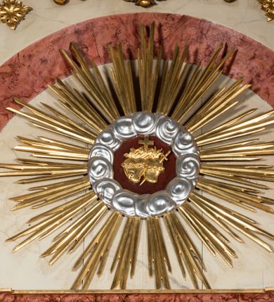 Zdjęcie nr 23: Nastawa ołtarzowa architektoniczna, jednoosiowa, jednokondygnacyjna ze zwieńczeniem. Ołtarz prostopadłościenny, drewniany z drewnianą mensą i z marmurowym portatylem. Antepedium w formie prostokąta ujętego profilowaną ramą. W polu marmoryzowana płycina o narożach zdobionych płaskorzeźbioną dekoracją roślinną złożoną z liści akantu oraz nałożonymi na siebie łacińskim krzyżem z kotwicą i gorejącym sercem oplecionym wicią z róż w polu. Tabernakulum w kształcie prostopadłościennej skrzynki na niskim cokole, flankowane dwoma pilastrami ustawionymi pod kątem, zdobionymi wicią z liści akantu; zamknięte od góry prostym belkowaniem, pośrodku falującym. Na drzwiczkach płycina w kształcie stojącego prostokąta, zamkniętego łukiem półkolistym, ujęta profilowaną ramą, w polu której umieszczone jest płaskorzeźbione gorejące serce osadzone na gałązce róży; tło czerwone.

Retabulum na zdwojonym cokole, flankowane ustawionymi pod kątem w jednej linii parami pilastrów, filarów oraz kolumn na przodzie. Podpory dźwigają wyłamane na osi belkowanie z ustawionymi na bokach rzeźbami aniołków. Trzony filarów są marmoryzowane; trzony kolumn delikatnie zwężające się ku górze, złocone, zdobione pionowymi pasami, co drugi wypełniony pnącą się ku górze rytą wicią z liści dębu lub z liści klonu; kapitele podpór kompozytowe.  Po bokach ołtarza na niskich cokołach ustawione pod kątem rzeźby św. Katarzyny Aleksandryjskiej po lewej i św. Wawrzyńca po prawej stronie. W polu, w głębokiej wnęce ujętej szeroką, profilowaną ramą umieszczony jest obraz św. Józefa z Dzieciątkiem. Wnęka od wewnątrz zdobiona płaskorzeźbioną winną latoroślą. Cokół dekorowany jest prostokątnymi, marmoryzowanymi płycinami; fryz złoconymi rozetami.

Zwieńczenie monumentalne, o fantazyjnym kształcie, po bokach ujęte wolutami zdobionymi liśćmi akantu, zamknięte od góry prostym gzymsem w formie nadwieszonego łuku z zatkniętym na szczycie łacińskim krzyżykiem. W polu, w półkolistej wnęce promienista gloria z dwoma gorejącymi sercami, z których jedno przebite jest mieczem, umieszczonym w otoku z obłoków.

Struktura w kolorze jasnobeżowym, płyciny, filary i detale marmoryzowana w kolorze różowym; ornamentyka i profilowania złocone i srebrzone.

