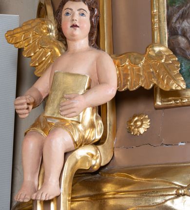 Zdjęcie nr 13: Ambona wisząca, przyścienna z wejściem od strony  kaplicy po północnej stronie prezbiterium. Kosz na planie półkolistym, na profilowanym cokole, z szyszką u spodu, flankowany po bokach dwoma spływami wolutowymi, na których ustawione są rzeźby siedzących aniołków. Na ściance kosza w profilowanej, złoconej ramie płaskorzeźba z przedstawieniem Połowu ryb. Zaplecek w kształcie prostokąta stojącego ujęty po bokach tkaniną przewiązaną u góry; w polu przedzielony złoconymi pasami ułożonymi na kształt litery H. W dolnej części zdobiony prostokątną płyciną ozdobioną płaskorzeźbioną rozetą, w górnej partii fantazyjną wicią roślinną. Baldachim  o wykroju półkolistym, w strefie belkowania zdobiony prostym fryzem przedzielonym pionowymi paskami na małe prostokątne płyciny, od dołu zdobiony lambrekinem, z dwoma wazonami płomienistymi z przodu oraz rzeźbą Mojżesza na skale w zwieńczeniu. U spodu baldachimu Gołębica Ducha Świętego w promienistej glorii złożonej z wiązek promieni o nierównej długości.
Płaskorzeźba na ściance frontowej kosza z przedstawieniem Połowu ryb. Kompozycja wielopostaciowa z ukazaniem po prawej stronie Jezusa nauczającego w łodzi oraz trzech uczniów wyciągających sieć pełną ryb. Po lewej stronie na brzegu siedząca postać jednego z uczniów. Uczniowie ubrani w długie suknie z długimi rękawami w kolorach: czerwonym, niebieskim i zielonym. Jezus ubrany jest w długą, złotą suknię z długim rękawem i złoty płaszcz. Krajobraz ukazany sumarycznie z wyraźnie zaznaczonymi falami morskimi. Tło złocone, ze złoconymi obłokami.
Aniołki siedzące na wolutach ukazane frontalnie, z  rozpostartymi szeroko skrzydłami. Aniołek po lewej stronie z rękami lekko ugiętymi w łokciach, z zamkniętą księgą w lewej dłoni. Aniołek po prawej stronie, delikatnie przechylony w lewo, z otwartą księgą w lewej dłoni i prawą ręką uniesioną nad księgą. Aniołki przepasane w pasie złotą chustą. Twarze szerokie, z pucułowatymi i delikatnie zarumienionymi policzkami, małe i wąskie usta, krótkie nosy. Włosy średniej długości, ciemnobrązowe, kędzierzawe.
W zwieńczeniu na wysokiej skale ustawiona jest rzeźba Mojżesza, ukazana frontalnie, z lewą nogą wspartą na skale, z tablicą przykazań w lewym ręku i laską w prawej. Mojżesz ubrany w długą, złotą suknię z długim rękawem. Twarz podłużna, okolona długą, ciemnobrązową brodą i krótkimi, ciemnobrązowymi włosami.
Struktura ambony polichromowana w kolorze jasnobrązowym, detale w kolorze ciemnobrązowym,  profile i ornamenty złocone oraz posrebrzone.