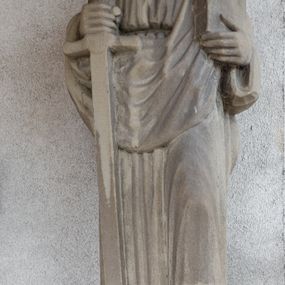 Zdjęcie nr 1: Rzeźba przedstawiająca św. Pawła, pełna, ustawiona na prostopadłościennym cokole. Święty ukazany w delikatnym kontrapoście z lewą nogą ugiętą w kolanie, z mieczem w prawej dłoni i księgą w lewej. Twarz podłużna, okolona długą brodą, usta delikatnie rozchylone, nos długi i prosty, włosy krótkie. Święty ubrany jest w długą suknię z długimi rękawami, przewiązaną w talii oraz płaszcz przerzucony przez prawe ramię i spływający połą z przodu na lewe ramię. Draperia szat sztywna, biegnąca równoległymi fałdami w dół. 