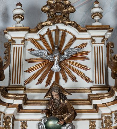 Zdjęcie nr 6: Nastawa ołtarzowa architektoniczna, jednoosiowa, jednokondygnacyjna ze zwieńczeniem, ustawiona na trójstrefowym cokole, dolnym murowanym. Mensa ołtarzowa kamienna, wsparta na dwóch konsolach, o profilowanym brzegu z inskrypcją „S(ANC)TI MART(YRES) STANISLAE EP(ISCOPE) CRACOVIAEN(SI) ET THOMA EP(ISCOPE) CANTUARIEN(SI) ORATE PRO NOBIS”. Tabernakulum w formie  drewnianej, prostopadłościennej skrzynki, ustawione na niskim cokole, zamknięte niewielkim gzymsem. Drzwiczki dwuskrzydłowe z aplikowanymi literami alfa i omega. Cokół nastawy zdobiony w dolnej partii parą konsolek z liśćmi akantu, powyżej prostokątne płyciny z rzeźbionymi główkami aniołków. Pośrodku cokół dekorowany prostokątną płyciną zamkniętą łukiem dwuramiennym z uskokiem. W polu płaskorzeźbiona dekoracja złożona z korony cierniowej na tle promienistej glorii oraz stylizowanych wici roślinnych akantu oraz rocaille’u.

Kondygnacja ujęta zwielokrotnionymi parami pilastrów o kanelowanych trzonach i stylizowanych kapitelach kompozytowych. Podpory wspierają pełne belkowanie wyłamane na ich osi oraz przerwany, półkolisty przyczółek na osi zewnętrznej. W polu środkowym płytka nisza w formie stojącego prostokąta zamknięta łukiem odcinkowym nadwieszonym, ujęta profilowaną ramą, wewnątrz obraz z przedstawieniem św. Antoniego Padewskiego. Zwieńczenie ustawione na niewielkim cokole, w formie stojącego prostokąta flankowanego parą kanelowanych pilastrów, wspierających profilowany gzyms i ustawione po bokach wazony. Całość zakończona ornamentalnym szczytem ze stylizowaną muszlą palmetową. W polu płaskorzeźbiona gołębica Ducha Świętego na tle promienistej glorii. Poniżej w partii fryzu rzeźba Boga Ojca. Po bokach zwieńczenia spływy wolutowe ozdobione kampanulami. Struktura polichromowana w kolorze białym, kolumny, profile i ornamentyka złocone, detale srebrzone.
