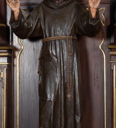 Zdjęcie nr 5: Nastawa architektoniczna, trójosiowa, jednokondygnacyjna ze zwieńczeniem, ustawiona na wysokiej predelli. Ołtarz w formie płytkiej skrzyni ustawionej na stopniu, dekorowanej z przodu dwiema półkolumienkami oraz trzema płycinami – dwiema z blendami i środkowej z godłem franciszkańskim. Mensa drewniana, wysunięta do przodu, wsparta na dwóch kolumnach. Predella dekorowana płycinami z blendami. Na jej tle, na mensie stoi figura św. Franciszka. Osie nastawy wydzielone trzema parami kolumienek podtrzymujących wimpergi z pinaklami, zakończone szczytami. Oś środkowa najwyższa, w jej polu obraz św. Ludwika w formie stojącego prostokąta zamkniętego łukiem trójlistnym ostrym, w prostej ramie dekorowanej na łuku ornamentem roślinnym. Zakończona szczytem w formie wieżyczki z przyporami i z ażurowymi blendami, zwieńczonej pinaklami dekorowanymi kwiatonami. Na osiach bocznych nisze z figurami św. Elżbiety i św. Katarzyny Aleksandryjskiej; flankowane ażurowymi blendami i maswerkami, po zewnętrznej stronie z pinaklami. Osie zakończone szczytami w formie wieżyczek z przyporami i ażurowymi blendami oraz pinaklami dekorowanymi kwiatonami. 
Struktura nastawy pokryta ciemnobrązową politurą, ornamentyka i profile złocone, wnętrza nisz polichromowane w kolorze czerwonym i niebieskim. 
