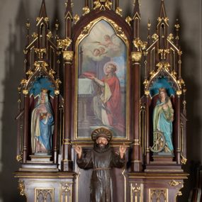 Zdjęcie nr 1: Nastawa architektoniczna, trójosiowa, jednokondygnacyjna ze zwieńczeniem, ustawiona na wysokiej predelli. Ołtarz w formie płytkiej skrzyni ustawionej na stopniu, dekorowanej z przodu dwiema półkolumienkami oraz trzema płycinami – dwiema z blendami i środkowej z godłem franciszkańskim. Mensa drewniana, wysunięta do przodu, wsparta na dwóch kolumnach. Predella dekorowana płycinami z blendami. Na jej tle, na mensie stoi figura św. Franciszka. Osie nastawy wydzielone trzema parami kolumienek podtrzymujących wimpergi z pinaklami, zakończone szczytami. Oś środkowa najwyższa, w jej polu obraz św. Ludwika w formie stojącego prostokąta zamkniętego łukiem trójlistnym ostrym, w prostej ramie dekorowanej na łuku ornamentem roślinnym. Zakończona szczytem w formie wieżyczki z przyporami i z ażurowymi blendami, zwieńczonej pinaklami dekorowanymi kwiatonami. Na osiach bocznych nisze z figurami św. Elżbiety i św. Katarzyny Aleksandryjskiej; flankowane ażurowymi blendami i maswerkami, po zewnętrznej stronie z pinaklami. Osie zakończone szczytami w formie wieżyczek z przyporami i ażurowymi blendami oraz pinaklami dekorowanymi kwiatonami. 
Struktura nastawy pokryta ciemnobrązową politurą, ornamentyka i profile złocone, wnętrza nisz polichromowane w kolorze czerwonym i niebieskim. 
