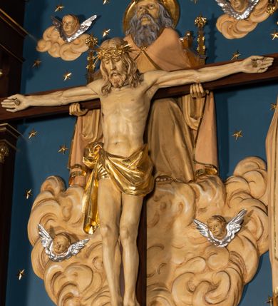 Zdjęcie nr 7: Nastawa architektoniczna, jednoosiowa, jednokondygnacyjna, ze zwieńczeniem, ustawiona na wysokim cokole. Ołtarz ustawiony na pięciostopniowej kamiennej podstawie; granitowy, prostopadłościenny, z monogramem IHS na froncie, mensa granitowa. Na nim drewniane tabernakulum w formie prostopadłościennej skrzynki, flankowane parą kolumienek, zamknięte od góry profilowanym gzymsem. Na ściance frontowej wysunięte do przodu metalowe drzwiczki w oprawie architektonicznej na niskim cokole, zamknięte od góry prostym gzymsem. Na drzwiczkach kielich z hostią, w płycinie o kształcie prostokąta stojącego zamkniętego łukiem trójlistnym ostrym. 
Nastawa flankowana dwiema dwukondygnacyjnymi wieżyczkami na planie ośmioboku z figurami św. Jana Ewangelisty i św. Piotra w pierwszej kondygnacji oraz figurami aniołów w drugiej. Figury apostołów ustawione są na ośmiobocznych wspornikach zdobionych od dołu arkadowaniem z kwiatonami, podtrzymywanych przez ośmioboczne kolumienki, flankujące kamienny ołtarz. Nad figurami ośmioboczne baldachimy zdobione od dołu arkadowaniem z kwiatonami, stanowiące podstawę dla figur aniołów, które zwieńczone są analogicznymi ośmiobocznymi baldachimami i rozbudowanymi pinaklami. W polu środkowym rzeźbiona Trójca Święta ukazana jako Tron łaski pośród obłoków i uskrzydlonych główek anielskich. Nad nią duży, ośmioboczny baldachim, zdobiony od dołu arkadowaniem, zakończonym kwiatonami, dekorowany maswerkami, wimpergami i kwiatonami, naprzemiennie z pinaklami, który stanowi podstawę wieżyczki wieńczącej ołtarz. W jej polu ustawiona figura Matki Boskiej, nad nią ośmioboczny baldachim zdobiony od dołu arkadowaniem i kwiatonami, zakończony dużym pinaklem dekorowanym żabkami. Nastawa flankowana uszami w formie przypór dekorowanych maswerkiem i wąskimi kolumienkami z pinaklami. 
Struktura politurowana w kolorze ciemnobrązowym, detale i ornamentyka złocone, tło pola głównego oraz podniebienia baldachimów błękitne.