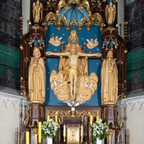 Zdjęcie nr 1: Nastawa architektoniczna, jednoosiowa, jednokondygnacyjna, ze zwieńczeniem, ustawiona na wysokim cokole. Ołtarz ustawiony na pięciostopniowej kamiennej podstawie; granitowy, prostopadłościenny, z monogramem IHS na froncie, mensa granitowa. Na nim drewniane tabernakulum w formie prostopadłościennej skrzynki, flankowane parą kolumienek, zamknięte od góry profilowanym gzymsem. Na ściance frontowej wysunięte do przodu metalowe drzwiczki w oprawie architektonicznej na niskim cokole, zamknięte od góry prostym gzymsem. Na drzwiczkach kielich z hostią, w płycinie o kształcie prostokąta stojącego zamkniętego łukiem trójlistnym ostrym. 
Nastawa flankowana dwiema dwukondygnacyjnymi wieżyczkami na planie ośmioboku z figurami św. Jana Ewangelisty i św. Piotra w pierwszej kondygnacji oraz figurami aniołów w drugiej. Figury apostołów ustawione są na ośmiobocznych wspornikach zdobionych od dołu arkadowaniem z kwiatonami, podtrzymywanych przez ośmioboczne kolumienki, flankujące kamienny ołtarz. Nad figurami ośmioboczne baldachimy zdobione od dołu arkadowaniem z kwiatonami, stanowiące podstawę dla figur aniołów, które zwieńczone są analogicznymi ośmiobocznymi baldachimami i rozbudowanymi pinaklami. W polu środkowym rzeźbiona Trójca Święta ukazana jako Tron łaski pośród obłoków i uskrzydlonych główek anielskich. Nad nią duży, ośmioboczny baldachim, zdobiony od dołu arkadowaniem, zakończonym kwiatonami, dekorowany maswerkami, wimpergami i kwiatonami, naprzemiennie z pinaklami, który stanowi podstawę wieżyczki wieńczącej ołtarz. W jej polu ustawiona figura Matki Boskiej, nad nią ośmioboczny baldachim zdobiony od dołu arkadowaniem i kwiatonami, zakończony dużym pinaklem dekorowanym żabkami. Nastawa flankowana uszami w formie przypór dekorowanych maswerkiem i wąskimi kolumienkami z pinaklami. 
Struktura politurowana w kolorze ciemnobrązowym, detale i ornamentyka złocone, tło pola głównego oraz podniebienia baldachimów błękitne.