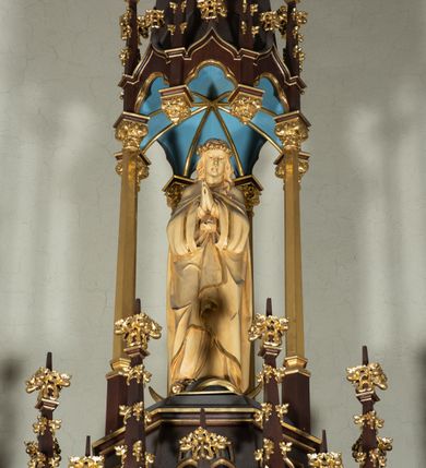 Zdjęcie nr 13: Nastawa architektoniczna, jednoosiowa, jednokondygnacyjna, ze zwieńczeniem, ustawiona na wysokim cokole. Ołtarz ustawiony na pięciostopniowej kamiennej podstawie; granitowy, prostopadłościenny, z monogramem IHS na froncie, mensa granitowa. Na nim drewniane tabernakulum w formie prostopadłościennej skrzynki, flankowane parą kolumienek, zamknięte od góry profilowanym gzymsem. Na ściance frontowej wysunięte do przodu metalowe drzwiczki w oprawie architektonicznej na niskim cokole, zamknięte od góry prostym gzymsem. Na drzwiczkach kielich z hostią, w płycinie o kształcie prostokąta stojącego zamkniętego łukiem trójlistnym ostrym. 
Nastawa flankowana dwiema dwukondygnacyjnymi wieżyczkami na planie ośmioboku z figurami św. Jana Ewangelisty i św. Piotra w pierwszej kondygnacji oraz figurami aniołów w drugiej. Figury apostołów ustawione są na ośmiobocznych wspornikach zdobionych od dołu arkadowaniem z kwiatonami, podtrzymywanych przez ośmioboczne kolumienki, flankujące kamienny ołtarz. Nad figurami ośmioboczne baldachimy zdobione od dołu arkadowaniem z kwiatonami, stanowiące podstawę dla figur aniołów, które zwieńczone są analogicznymi ośmiobocznymi baldachimami i rozbudowanymi pinaklami. W polu środkowym rzeźbiona Trójca Święta ukazana jako Tron łaski pośród obłoków i uskrzydlonych główek anielskich. Nad nią duży, ośmioboczny baldachim, zdobiony od dołu arkadowaniem, zakończonym kwiatonami, dekorowany maswerkami, wimpergami i kwiatonami, naprzemiennie z pinaklami, który stanowi podstawę wieżyczki wieńczącej ołtarz. W jej polu ustawiona figura Matki Boskiej, nad nią ośmioboczny baldachim zdobiony od dołu arkadowaniem i kwiatonami, zakończony dużym pinaklem dekorowanym żabkami. Nastawa flankowana uszami w formie przypór dekorowanych maswerkiem i wąskimi kolumienkami z pinaklami. 
Struktura politurowana w kolorze ciemnobrązowym, detale i ornamentyka złocone, tło pola głównego oraz podniebienia baldachimów błękitne.