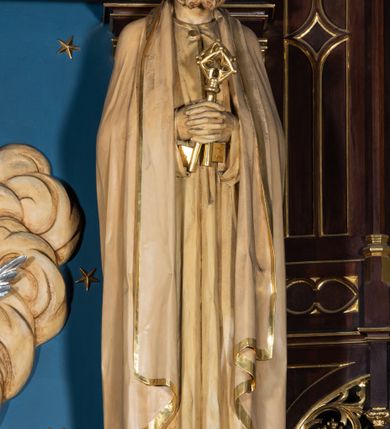 Zdjęcie nr 14: Nastawa architektoniczna, jednoosiowa, jednokondygnacyjna, ze zwieńczeniem, ustawiona na wysokim cokole. Ołtarz ustawiony na pięciostopniowej kamiennej podstawie; granitowy, prostopadłościenny, z monogramem IHS na froncie, mensa granitowa. Na nim drewniane tabernakulum w formie prostopadłościennej skrzynki, flankowane parą kolumienek, zamknięte od góry profilowanym gzymsem. Na ściance frontowej wysunięte do przodu metalowe drzwiczki w oprawie architektonicznej na niskim cokole, zamknięte od góry prostym gzymsem. Na drzwiczkach kielich z hostią, w płycinie o kształcie prostokąta stojącego zamkniętego łukiem trójlistnym ostrym. 
Nastawa flankowana dwiema dwukondygnacyjnymi wieżyczkami na planie ośmioboku z figurami św. Jana Ewangelisty i św. Piotra w pierwszej kondygnacji oraz figurami aniołów w drugiej. Figury apostołów ustawione są na ośmiobocznych wspornikach zdobionych od dołu arkadowaniem z kwiatonami, podtrzymywanych przez ośmioboczne kolumienki, flankujące kamienny ołtarz. Nad figurami ośmioboczne baldachimy zdobione od dołu arkadowaniem z kwiatonami, stanowiące podstawę dla figur aniołów, które zwieńczone są analogicznymi ośmiobocznymi baldachimami i rozbudowanymi pinaklami. W polu środkowym rzeźbiona Trójca Święta ukazana jako Tron łaski pośród obłoków i uskrzydlonych główek anielskich. Nad nią duży, ośmioboczny baldachim, zdobiony od dołu arkadowaniem, zakończonym kwiatonami, dekorowany maswerkami, wimpergami i kwiatonami, naprzemiennie z pinaklami, który stanowi podstawę wieżyczki wieńczącej ołtarz. W jej polu ustawiona figura Matki Boskiej, nad nią ośmioboczny baldachim zdobiony od dołu arkadowaniem i kwiatonami, zakończony dużym pinaklem dekorowanym żabkami. Nastawa flankowana uszami w formie przypór dekorowanych maswerkiem i wąskimi kolumienkami z pinaklami. 
Struktura politurowana w kolorze ciemnobrązowym, detale i ornamentyka złocone, tło pola głównego oraz podniebienia baldachimów błękitne.