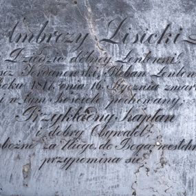 Zdjęcie nr 1: Epitafium w formie leżącego prostokąta, w narożach metalowe śluby. W polu inskrypcja „Ambroży Lisicki / Dziedzic dólnéy Łentowni, / Proboszcz Jordanowski, Pleban Łentowski, / w Roku 1817. Dnia 16. Stycznia zmarły, / i w tym Kościele pochowany; / Przykładny Kapłan / i dobry Obywatel; / o pobożne za Niego, do Boga westchnienie, / przypomina się.”