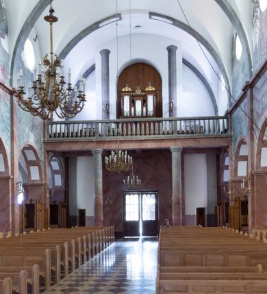 Zdjęcie nr 1: Prospekt organowy architektoniczny, pięcioosiowy, jednokondygnacyjny, na wysokim cokole. Osie zewnętrzne i środkowa szersze i wyższe od wewnętrznych, zamknięte niepełnym belkowaniem, środkowa nieco niższa, zamknięta szczytem utworzonym z krzyża podtrzymywanego przez wić roślinną; zewnętrzne zamknięte szczytami utworzonymi ze zwijających się wolutowo liści akantu zakończonych palmetą. Prześwity na piszczałki w formie stojącego prostokąta, dekorowane w górnych narożach ornamentem roślinnym. Dwie osie wewnętrzne dwukrotnie niższe i węższe, zakończone ukośnym i wklęsłym fragmentem gzymsu, z wąskimi prześwitami na piszczałki w formie stojącego prostokąta zamkniętego ukośnie. Struktura polichromowana w kolorze brązowym, profile i ornamentyka złocone.