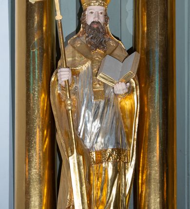 Zdjęcie nr 10: Ołtarz architektoniczny, jednoosiowy, z wydzieloną częścią cokołową i predellą, jednokondygnacyjny, ze zwieńczeniem, dostępny po dwóch kamiennych stopniach. Mensa drewniana z kamiennym portatylem, wsparta na tumbie z neorokokowym kartuszem na froncie. Tabernakulum w formie prostopadłościennej skrzynki, flankowanej z przodu płaskorzeźbionymi kolumienkami, nad nimi rozety; górna krawędź obwiedziona profilowanym gzymsem. Drzwiczki w kształcie formie stojącego prostokąta zamkniętego łukiem półkolistym nadwieszonym, ujęte ramą, z płaskorzeźbionym przedstawieniem kielicha i hostii w polu. Nastawa ujęta dwiema parami kolumn umieszczonych na tle pilastrów podtrzymujących pełne belkowanie, przerwane nad polem środkowym, występujące ponad kolumnami; skrajna para kolumn ustawiona ukośnie względem retabulum. W polu środkowym nisza w kształcie stojącego prostokąta zamkniętego łukiem wklęsło-wypukłym nadwieszonym, ujęta podwójną profilowaną ramą, w niszy obraz Trójcą Święta. Ponad obrazem, na osin neorokokowy kartusz z koroną i inicjałami: KK, otoczony czterema uskrzydlonymi główkami anielskimi. Pomiędzy kolumnami figury św. Wojciecha i św. Stanisława ustawione na konsolach. Zwieńczenie w kształcie aedikuli, ujęte parą łukowato wygiętych pilastrów oraz spływami wolutowymi, na gzymsie koronującym z płaskorzeźbionym Okiem Opatrzności w glorii promienistej oraz z parą wazonów po bokach. W polu owalny obraz z przedstawieniem Ecce Homo ujęty profilowaną ramą. W zwieńczeniu, w osiach kolumn para puttów i para wazonów. Trzony pilastrów i przyłucza w polu głównym dekorowane ornamentem neorokokowym; fryz zdobiony rozetami. Struktura polichromowana w kolorze seledynowym; kolumny, ornamenty i profile złocone.