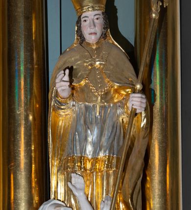 Zdjęcie nr 7: Ołtarz architektoniczny, jednoosiowy, z wydzieloną częścią cokołową i predellą, jednokondygnacyjny, ze zwieńczeniem, dostępny po dwóch kamiennych stopniach. Mensa drewniana z kamiennym portatylem, wsparta na tumbie z neorokokowym kartuszem na froncie. Tabernakulum w formie prostopadłościennej skrzynki, flankowanej z przodu płaskorzeźbionymi kolumienkami, nad nimi rozety; górna krawędź obwiedziona profilowanym gzymsem. Drzwiczki w kształcie formie stojącego prostokąta zamkniętego łukiem półkolistym nadwieszonym, ujęte ramą, z płaskorzeźbionym przedstawieniem kielicha i hostii w polu. Nastawa ujęta dwiema parami kolumn umieszczonych na tle pilastrów podtrzymujących pełne belkowanie, przerwane nad polem środkowym, występujące ponad kolumnami; skrajna para kolumn ustawiona ukośnie względem retabulum. W polu środkowym nisza w kształcie stojącego prostokąta zamkniętego łukiem wklęsło-wypukłym nadwieszonym, ujęta podwójną profilowaną ramą, w niszy obraz Trójcą Święta. Ponad obrazem, na osin neorokokowy kartusz z koroną i inicjałami: KK, otoczony czterema uskrzydlonymi główkami anielskimi. Pomiędzy kolumnami figury św. Wojciecha i św. Stanisława ustawione na konsolach. Zwieńczenie w kształcie aedikuli, ujęte parą łukowato wygiętych pilastrów oraz spływami wolutowymi, na gzymsie koronującym z płaskorzeźbionym Okiem Opatrzności w glorii promienistej oraz z parą wazonów po bokach. W polu owalny obraz z przedstawieniem Ecce Homo ujęty profilowaną ramą. W zwieńczeniu, w osiach kolumn para puttów i para wazonów. Trzony pilastrów i przyłucza w polu głównym dekorowane ornamentem neorokokowym; fryz zdobiony rozetami. Struktura polichromowana w kolorze seledynowym; kolumny, ornamenty i profile złocone.