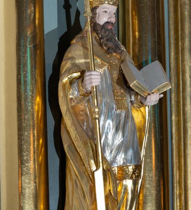 Zdjęcie nr 11: Ołtarz architektoniczny, jednoosiowy, z wydzieloną częścią cokołową i predellą, jednokondygnacyjny, ze zwieńczeniem, dostępny po dwóch kamiennych stopniach. Mensa drewniana z kamiennym portatylem, wsparta na tumbie z neorokokowym kartuszem na froncie. Tabernakulum w formie prostopadłościennej skrzynki, flankowanej z przodu płaskorzeźbionymi kolumienkami, nad nimi rozety; górna krawędź obwiedziona profilowanym gzymsem. Drzwiczki w kształcie formie stojącego prostokąta zamkniętego łukiem półkolistym nadwieszonym, ujęte ramą, z płaskorzeźbionym przedstawieniem kielicha i hostii w polu. Nastawa ujęta dwiema parami kolumn umieszczonych na tle pilastrów podtrzymujących pełne belkowanie, przerwane nad polem środkowym, występujące ponad kolumnami; skrajna para kolumn ustawiona ukośnie względem retabulum. W polu środkowym nisza w kształcie stojącego prostokąta zamkniętego łukiem wklęsło-wypukłym nadwieszonym, ujęta podwójną profilowaną ramą, w niszy obraz Trójcą Święta. Ponad obrazem, na osin neorokokowy kartusz z koroną i inicjałami: KK, otoczony czterema uskrzydlonymi główkami anielskimi. Pomiędzy kolumnami figury św. Wojciecha i św. Stanisława ustawione na konsolach. Zwieńczenie w kształcie aedikuli, ujęte parą łukowato wygiętych pilastrów oraz spływami wolutowymi, na gzymsie koronującym z płaskorzeźbionym Okiem Opatrzności w glorii promienistej oraz z parą wazonów po bokach. W polu owalny obraz z przedstawieniem Ecce Homo ujęty profilowaną ramą. W zwieńczeniu, w osiach kolumn para puttów i para wazonów. Trzony pilastrów i przyłucza w polu głównym dekorowane ornamentem neorokokowym; fryz zdobiony rozetami. Struktura polichromowana w kolorze seledynowym; kolumny, ornamenty i profile złocone.