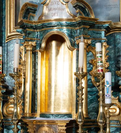 Zdjęcie nr 42: Nastawa ołtarzowa architektoniczna, jednokondygnacyjna ze zwieńczeniem, jednoosiowa z bramkami. Ołtarz prostopadłościenny, murowany, w drewnianej obudowie, z drewnianą mensą. Antepedium ujęte profilowaną ramą; w polu malowana płycina w formie leżącego prostokąta o zaokrąglonych narożach, wypełniona gałązkami różanymi, z akantowo-regencyjnym kartuszem. W narożach antepedium malowane ptaki siedzące na gałązkach. W polu kartusza ukazana scena męczeństwa św. Szymona i św. Judy Tadeusza, na tle pejzażu. Tabernakulum metalowe, prostopadłościenne, flankowane pilastrami w formie spływów wolutowych zdobionych gałązkami róży, zamknięte od góry profilowanym gzymsem. Drzwiczki w kształcie stojącego prostokąta zamkniętego łukiem odcinkowym nadwieszonym; w polu przedstawienie kielicha z hostią. Tabernakulum wprawione w wysoki cokół, na którym stoi tron wystawienia w formie obrotowej niszy, o wypukłej ściance frontowej i ustawionymi pod kątem ściankami bocznymi. Nisza flankowana parą kolumienek i spływów wolutowych dźwigających belkowanie oraz fragmenty przerwanego, półkolistego przyczółka. Na belkowaniu szczyt z rocaillem, z napisem w polu: „ECCE / TABERNACULUM / DEI”. Nastawa ustawiona na dwustrefowym cokole, z wyodrębnionymi czterema prostopadłościanami, w górnej części zdobionym płycinami. Retabulum ujęte parami pilastrów i filarów o kanelowanych trzonach oraz stojącymi przed nimi w układzie schodkowym kolumnami o kapitelach kompozytowych. Podpory dźwigają pełne belkowanie, wyłamane na ich osi, z przerwanym architrawem nad polem środkowym. Na belkowaniu fragmenty falistego, przerwanego przyczółka z figurami aniołów z arma Christi. W polu środkowym wnęka w formie stojącego prostokąta zamkniętego łukiem odcinkowym nadwieszonym, ujęta profilowaną ramą, z obrazem Najświętszej Marii Panny Niepokalanie Poczętej. Nad nią, w polu belkowania rocaille'owy kartusz z napisem „HI / SUNT VIRI / MISERICORDIAE / [...]ccdis 44”. Zwieńczenie w formie zbliżonej do stojącego prostokąta, ujętego pilastrami przechodzącymi w spływy wolutowe, zamkniętego dwoma fragmentami wolutowego gzymsu. Całość zakończona szczytem utworzonym z muszli i zwisów kwiatowych, flankowanym przez dwa wazony. Zwieńczenie ujęte liśćmi palmowymi. W polu obraz z grupą Ukrzyżowania w formie stojącego prostokąta, w profilowanej ramie, dekorowanej rocaille'm. Nastawa flankowana bramkami zwieńczonymi konsolami, na których stoją figury Marii i św. Jana Ewangelisty. Przejścia w formie stojącego prostokąta o wklęsłych górnych narożach, z drzwiczkami z malowanymi przedstawieniami św. Piotra i św. Pawła. Struktura polichromowana na sposób imitujący marmoryzację w kolorze zielono-niebieskim, z laserunkiem, kolumny, ornamentyka i profile złocone, detal srebrzony.
