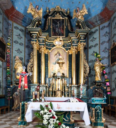 Zdjęcie nr 1: Nastawa ołtarzowa architektoniczna, jednokondygnacyjna ze zwieńczeniem, jednoosiowa z bramkami. Ołtarz prostopadłościenny, murowany, w drewnianej obudowie, z drewnianą mensą. Antepedium ujęte profilowaną ramą; w polu malowana płycina w formie leżącego prostokąta o zaokrąglonych narożach, wypełniona gałązkami różanymi, z akantowo-regencyjnym kartuszem. W narożach antepedium malowane ptaki siedzące na gałązkach. W polu kartusza ukazana scena męczeństwa św. Szymona i św. Judy Tadeusza, na tle pejzażu. Tabernakulum metalowe, prostopadłościenne, flankowane pilastrami w formie spływów wolutowych zdobionych gałązkami róży, zamknięte od góry profilowanym gzymsem. Drzwiczki w kształcie stojącego prostokąta zamkniętego łukiem odcinkowym nadwieszonym; w polu przedstawienie kielicha z hostią. Tabernakulum wprawione w wysoki cokół, na którym stoi tron wystawienia w formie obrotowej niszy, o wypukłej ściance frontowej i ustawionymi pod kątem ściankami bocznymi. Nisza flankowana parą kolumienek i spływów wolutowych dźwigających belkowanie oraz fragmenty przerwanego, półkolistego przyczółka. Na belkowaniu szczyt z rocaillem, z napisem w polu: „ECCE / TABERNACULUM / DEI”. Nastawa ustawiona na dwustrefowym cokole, z wyodrębnionymi czterema prostopadłościanami, w górnej części zdobionym płycinami. Retabulum ujęte parami pilastrów i filarów o kanelowanych trzonach oraz stojącymi przed nimi w układzie schodkowym kolumnami o kapitelach kompozytowych. Podpory dźwigają pełne belkowanie, wyłamane na ich osi, z przerwanym architrawem nad polem środkowym. Na belkowaniu fragmenty falistego, przerwanego przyczółka z figurami aniołów z arma Christi. W polu środkowym wnęka w formie stojącego prostokąta zamkniętego łukiem odcinkowym nadwieszonym, ujęta profilowaną ramą, z obrazem Najświętszej Marii Panny Niepokalanie Poczętej. Nad nią, w polu belkowania rocaille'owy kartusz z napisem „HI / SUNT VIRI / MISERICORDIAE / [...]ccdis 44”. Zwieńczenie w formie zbliżonej do stojącego prostokąta, ujętego pilastrami przechodzącymi w spływy wolutowe, zamkniętego dwoma fragmentami wolutowego gzymsu. Całość zakończona szczytem utworzonym z muszli i zwisów kwiatowych, flankowanym przez dwa wazony. Zwieńczenie ujęte liśćmi palmowymi. W polu obraz z grupą Ukrzyżowania w formie stojącego prostokąta, w profilowanej ramie, dekorowanej rocaille'm. Nastawa flankowana bramkami zwieńczonymi konsolami, na których stoją figury Marii i św. Jana Ewangelisty. Przejścia w formie stojącego prostokąta o wklęsłych górnych narożach, z drzwiczkami z malowanymi przedstawieniami św. Piotra i św. Pawła. Struktura polichromowana na sposób imitujący marmoryzację w kolorze zielono-niebieskim, z laserunkiem, kolumny, ornamentyka i profile złocone, detal srebrzony.