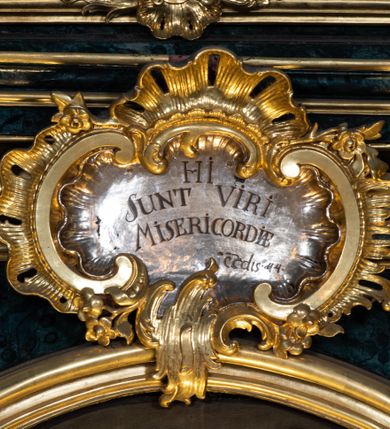 Zdjęcie nr 78: Nastawa ołtarzowa architektoniczna, jednokondygnacyjna ze zwieńczeniem, jednoosiowa z bramkami. Ołtarz prostopadłościenny, murowany, w drewnianej obudowie, z drewnianą mensą. Antepedium ujęte profilowaną ramą; w polu malowana płycina w formie leżącego prostokąta o zaokrąglonych narożach, wypełniona gałązkami różanymi, z akantowo-regencyjnym kartuszem. W narożach antepedium malowane ptaki siedzące na gałązkach. W polu kartusza ukazana scena męczeństwa św. Szymona i św. Judy Tadeusza, na tle pejzażu. Tabernakulum metalowe, prostopadłościenne, flankowane pilastrami w formie spływów wolutowych zdobionych gałązkami róży, zamknięte od góry profilowanym gzymsem. Drzwiczki w kształcie stojącego prostokąta zamkniętego łukiem odcinkowym nadwieszonym; w polu przedstawienie kielicha z hostią. Tabernakulum wprawione w wysoki cokół, na którym stoi tron wystawienia w formie obrotowej niszy, o wypukłej ściance frontowej i ustawionymi pod kątem ściankami bocznymi. Nisza flankowana parą kolumienek i spływów wolutowych dźwigających belkowanie oraz fragmenty przerwanego, półkolistego przyczółka. Na belkowaniu szczyt z rocaillem, z napisem w polu: „ECCE / TABERNACULUM / DEI”. Nastawa ustawiona na dwustrefowym cokole, z wyodrębnionymi czterema prostopadłościanami, w górnej części zdobionym płycinami. Retabulum ujęte parami pilastrów i filarów o kanelowanych trzonach oraz stojącymi przed nimi w układzie schodkowym kolumnami o kapitelach kompozytowych. Podpory dźwigają pełne belkowanie, wyłamane na ich osi, z przerwanym architrawem nad polem środkowym. Na belkowaniu fragmenty falistego, przerwanego przyczółka z figurami aniołów z arma Christi. W polu środkowym wnęka w formie stojącego prostokąta zamkniętego łukiem odcinkowym nadwieszonym, ujęta profilowaną ramą, z obrazem Najświętszej Marii Panny Niepokalanie Poczętej. Nad nią, w polu belkowania rocaille&#039;owy kartusz z napisem „HI / SUNT VIRI / MISERICORDIAE / [...]ccdis 44”. Zwieńczenie w formie zbliżonej do stojącego prostokąta, ujętego pilastrami przechodzącymi w spływy wolutowe, zamkniętego dwoma fragmentami wolutowego gzymsu. Całość zakończona szczytem utworzonym z muszli i zwisów kwiatowych, flankowanym przez dwa wazony. Zwieńczenie ujęte liśćmi palmowymi. W polu obraz z grupą Ukrzyżowania w formie stojącego prostokąta, w profilowanej ramie, dekorowanej rocaille&#039;m. Nastawa flankowana bramkami zwieńczonymi konsolami, na których stoją figury Marii i św. Jana Ewangelisty. Przejścia w formie stojącego prostokąta o wklęsłych górnych narożach, z drzwiczkami z malowanymi przedstawieniami św. Piotra i św. Pawła. Struktura polichromowana na sposób imitujący marmoryzację w kolorze zielono-niebieskim, z laserunkiem, kolumny, ornamentyka i profile złocone, detal srebrzony.