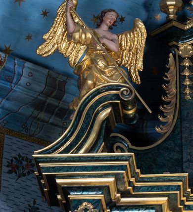 Zdjęcie nr 28: Nastawa ołtarzowa architektoniczna, jednokondygnacyjna ze zwieńczeniem, jednoosiowa z bramkami. Ołtarz prostopadłościenny, murowany, w drewnianej obudowie, z drewnianą mensą. Antepedium ujęte profilowaną ramą; w polu malowana płycina w formie leżącego prostokąta o zaokrąglonych narożach, wypełniona gałązkami różanymi, z akantowo-regencyjnym kartuszem. W narożach antepedium malowane ptaki siedzące na gałązkach. W polu kartusza ukazana scena męczeństwa św. Szymona i św. Judy Tadeusza, na tle pejzażu. Tabernakulum metalowe, prostopadłościenne, flankowane pilastrami w formie spływów wolutowych zdobionych gałązkami róży, zamknięte od góry profilowanym gzymsem. Drzwiczki w kształcie stojącego prostokąta zamkniętego łukiem odcinkowym nadwieszonym; w polu przedstawienie kielicha z hostią. Tabernakulum wprawione w wysoki cokół, na którym stoi tron wystawienia w formie obrotowej niszy, o wypukłej ściance frontowej i ustawionymi pod kątem ściankami bocznymi. Nisza flankowana parą kolumienek i spływów wolutowych dźwigających belkowanie oraz fragmenty przerwanego, półkolistego przyczółka. Na belkowaniu szczyt z rocaillem, z napisem w polu: „ECCE / TABERNACULUM / DEI”. Nastawa ustawiona na dwustrefowym cokole, z wyodrębnionymi czterema prostopadłościanami, w górnej części zdobionym płycinami. Retabulum ujęte parami pilastrów i filarów o kanelowanych trzonach oraz stojącymi przed nimi w układzie schodkowym kolumnami o kapitelach kompozytowych. Podpory dźwigają pełne belkowanie, wyłamane na ich osi, z przerwanym architrawem nad polem środkowym. Na belkowaniu fragmenty falistego, przerwanego przyczółka z figurami aniołów z arma Christi. W polu środkowym wnęka w formie stojącego prostokąta zamkniętego łukiem odcinkowym nadwieszonym, ujęta profilowaną ramą, z obrazem Najświętszej Marii Panny Niepokalanie Poczętej. Nad nią, w polu belkowania rocaille'owy kartusz z napisem „HI / SUNT VIRI / MISERICORDIAE / [...]ccdis 44”. Zwieńczenie w formie zbliżonej do stojącego prostokąta, ujętego pilastrami przechodzącymi w spływy wolutowe, zamkniętego dwoma fragmentami wolutowego gzymsu. Całość zakończona szczytem utworzonym z muszli i zwisów kwiatowych, flankowanym przez dwa wazony. Zwieńczenie ujęte liśćmi palmowymi. W polu obraz z grupą Ukrzyżowania w formie stojącego prostokąta, w profilowanej ramie, dekorowanej rocaille'm. Nastawa flankowana bramkami zwieńczonymi konsolami, na których stoją figury Marii i św. Jana Ewangelisty. Przejścia w formie stojącego prostokąta o wklęsłych górnych narożach, z drzwiczkami z malowanymi przedstawieniami św. Piotra i św. Pawła. Struktura polichromowana na sposób imitujący marmoryzację w kolorze zielono-niebieskim, z laserunkiem, kolumny, ornamentyka i profile złocone, detal srebrzony.