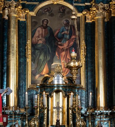 Zdjęcie nr 68: Nastawa ołtarzowa architektoniczna, jednokondygnacyjna ze zwieńczeniem, jednoosiowa z bramkami. Ołtarz prostopadłościenny, murowany, w drewnianej obudowie, z drewnianą mensą. Antepedium ujęte profilowaną ramą; w polu malowana płycina w formie leżącego prostokąta o zaokrąglonych narożach, wypełniona gałązkami różanymi, z akantowo-regencyjnym kartuszem. W narożach antepedium malowane ptaki siedzące na gałązkach. W polu kartusza ukazana scena męczeństwa św. Szymona i św. Judy Tadeusza, na tle pejzażu. Tabernakulum metalowe, prostopadłościenne, flankowane pilastrami w formie spływów wolutowych zdobionych gałązkami róży, zamknięte od góry profilowanym gzymsem. Drzwiczki w kształcie stojącego prostokąta zamkniętego łukiem odcinkowym nadwieszonym; w polu przedstawienie kielicha z hostią. Tabernakulum wprawione w wysoki cokół, na którym stoi tron wystawienia w formie obrotowej niszy, o wypukłej ściance frontowej i ustawionymi pod kątem ściankami bocznymi. Nisza flankowana parą kolumienek i spływów wolutowych dźwigających belkowanie oraz fragmenty przerwanego, półkolistego przyczółka. Na belkowaniu szczyt z rocaillem, z napisem w polu: „ECCE / TABERNACULUM / DEI”. Nastawa ustawiona na dwustrefowym cokole, z wyodrębnionymi czterema prostopadłościanami, w górnej części zdobionym płycinami. Retabulum ujęte parami pilastrów i filarów o kanelowanych trzonach oraz stojącymi przed nimi w układzie schodkowym kolumnami o kapitelach kompozytowych. Podpory dźwigają pełne belkowanie, wyłamane na ich osi, z przerwanym architrawem nad polem środkowym. Na belkowaniu fragmenty falistego, przerwanego przyczółka z figurami aniołów z arma Christi. W polu środkowym wnęka w formie stojącego prostokąta zamkniętego łukiem odcinkowym nadwieszonym, ujęta profilowaną ramą, z obrazem Najświętszej Marii Panny Niepokalanie Poczętej. Nad nią, w polu belkowania rocaille'owy kartusz z napisem „HI / SUNT VIRI / MISERICORDIAE / [...]ccdis 44”. Zwieńczenie w formie zbliżonej do stojącego prostokąta, ujętego pilastrami przechodzącymi w spływy wolutowe, zamkniętego dwoma fragmentami wolutowego gzymsu. Całość zakończona szczytem utworzonym z muszli i zwisów kwiatowych, flankowanym przez dwa wazony. Zwieńczenie ujęte liśćmi palmowymi. W polu obraz z grupą Ukrzyżowania w formie stojącego prostokąta, w profilowanej ramie, dekorowanej rocaille'm. Nastawa flankowana bramkami zwieńczonymi konsolami, na których stoją figury Marii i św. Jana Ewangelisty. Przejścia w formie stojącego prostokąta o wklęsłych górnych narożach, z drzwiczkami z malowanymi przedstawieniami św. Piotra i św. Pawła. Struktura polichromowana na sposób imitujący marmoryzację w kolorze zielono-niebieskim, z laserunkiem, kolumny, ornamentyka i profile złocone, detal srebrzony.