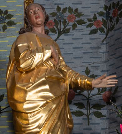 Zdjęcie nr 1: Rzeźba drążona, ustawiona na niskiej podstawie na planie prostokąta. Święty zwrócony w trzech czwartych w prawo, w delikatnym kontrapoście, z lekko uniesioną głową, z lewą ręką wyciągniętą w bok, prawą złożoną na piersi. Twarz ma owalną, z wyraźnie zaznaczoną brodą, o małych oczach zwróconych w górę, z głęboko rzeźbioną górną powieką, dużym nosem i pełnymi ustami z szeroką górną wargą. Włosy ma ciemnobrązowe, silnie kręcone, opadające na ramiona. Ubrany jest w złoconą tunikę z długimi rękawami, przepasaną w talii oraz złocony płaszcz zawiązany z przodu postaci, na lewym biodrze. Na stopach ma złocone sandały. Polichromia naturalistyczna w partiach ciała. 