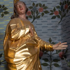 Zdjęcie nr 1: Rzeźba drążona, ustawiona na niskiej podstawie na planie prostokąta. Święty zwrócony w trzech czwartych w prawo, w delikatnym kontrapoście, z lekko uniesioną głową, z lewą ręką wyciągniętą w bok, prawą złożoną na piersi. Twarz ma owalną, z wyraźnie zaznaczoną brodą, o małych oczach zwróconych w górę, z głęboko rzeźbioną górną powieką, dużym nosem i pełnymi ustami z szeroką górną wargą. Włosy ma ciemnobrązowe, silnie kręcone, opadające na ramiona. Ubrany jest w złoconą tunikę z długimi rękawami, przepasaną w talii oraz złocony płaszcz zawiązany z przodu postaci, na lewym biodrze. Na stopach ma złocone sandały. Polichromia naturalistyczna w partiach ciała. 