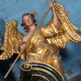 Zdjęcie nr 1: Rzeźby drążone z tyłu, klęczące na fragmentach przerwanego przyczółka, zwrócone do wewnątrz, pochylone. Lewy anioł w uniesionej lewej ręce trzyma laskę zakończoną gąbką, prawą kładzie na piersi. Prawy anioł obiema rękami trzyma włócznię. Twarze mają pociągłe, z wyodrębnionymi brodami, o małych oczach z głęboko rzeźbionymi górnymi powiekami, krótkimi nosami i pełnymi ustami, okolone kręconymi, brązowymi włosami, sięgającymi ramion. Anioły ubrane są w złocone tuniki z jednym rękawem, odsłaniające połowę torsu i drugie ramię, przepasane w talii. Skrzydła mają duże i złożone po bokach. Polichromia ciał naturalistyczna. 

