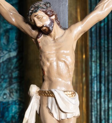 Zdjęcie nr 1: Figura umarłego Chrystusa przybita trzema gwoździami do krzyża o trójlistnym zakończeniu ramion. Ciało Jezusa w dużym zwisie, z ramionami układającymi się na kształt szerokiej litery „V”, z głową opadającą na prawe ramię, ze stopami skrzyżowanymi w układzie prawa na lewą. Twarz ma szczupłą, o zamkniętych oczach i dużym nosie, okoloną krótką brodą i brązowymi włosami opadającymi na ramiona. Na głowie ma koronę cierniową. Ciało szczupłe, ale silnie umięśnione, z podkreślonymi żebrami i mostkiem klatki piersiowej. Perizonium białe, krótkie, zawieszone na podwójnym, złoconym sznurze, odsłaniające prawe biodro, ze zwisem tkaniny na prawym boku. Polichromia ciała naturalistyczna z zaznaczonymi śladami męki. 
