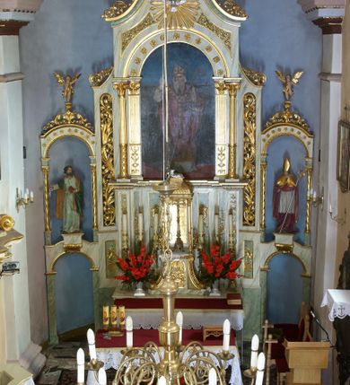 Zdjęcie nr 2: Ołtarz przyścienny, architektoniczny, jednoosiowy z bramkami, jednokondygnacyjny ze zwieńczeniem. Mensa prostopadłościenna, drewniana. Tabernakulum dwukondygnacyjne z tronem wystawienia. Kondygnacja pierwsza ujęta spływami wolutowymi, na drzwiczkach płycina w kształcie stojącego prostokąta zamkniętego łukiem półkolistym z płaskorzeźbionym kielichem z hostią w otoczeniu winorośli. W kondygnacji drugiej tron wystawienia zwieńczony baldachimem wspartym na smukłych kolumienkach z kompozytowymi kapitelami i takich samych pilastrach. Trzony podpór do jednej trzeciej wysokości dekorowane arabeską, powyżej kanelowane. U szczytu baldachimu srebrzony baranek leżący na księdze. Retabulum umieszczone na  wysokim cokole ozdobionym płycinami wypełnionymi dekoracją akantową. Cokół zwieńczony profilowanym gzymsem, na którym ustawione zdwojone podpory: w osiach środkowych złocone pilastry o kanelowanych trzonach dekorowanych w dolnej części arabeską oraz kompozytowych kapitelach; w osiach skrajnych kolumny o analogicznej jak w przypadku pilastrów dekoracji. Pole środkowe ołtarza w kształcie stojącego prostokąta zamkniętego łukiem półkolistym dekorowanym złoconymi kwiatami mieści obraz Matki Boskiej Śnieżnej oraz obraz św. Mikołaja (na zasuwie). Zwieńczenie w formie przyczółka utworzonego z dwóch, przeciwstawnie ustawionych wolut z centralnie umieszczonym złoconym krzyżem oraz ażurową, akantową strukturą; w polu płaskorzeźbiona gołębica Ducha Świętego na tle glorii promienistej. Oś środkowa ujęta dwiema wąskimi płycinami mieszczącymi złocony ornament akantowy. Bramki o formie architektonicznej, jednoosiowe, dwukondygnacyjne ze zwieńczeniem. Kondygnacja pierwsza w formie półkolistej arkady; w zworniku łuku złocona, wolutowa konsolka, na której  ustawiony prostopadłościenny postument z polichromowaną figurą św. Piotra (z lewej) i św. Stanisława (z prawej). Kondygnacja druga ujęta złoconymi korynckimi kolumienkami o skręconych trzonach dźwigającymi łuk półkolisty dekorowany złoconymi, płaskorzeźbionymi kwiatami. W zwieńczeniu pełnoplastyczne, polichromowane figurki puttów ustawione na kulistych konsolkach. Struktura ołtarza polichromowana (w tym marmoryzowana) w dwóch odcieniach jasnej zieleni. Elementy architektoniczne oraz ornamenty złocone.